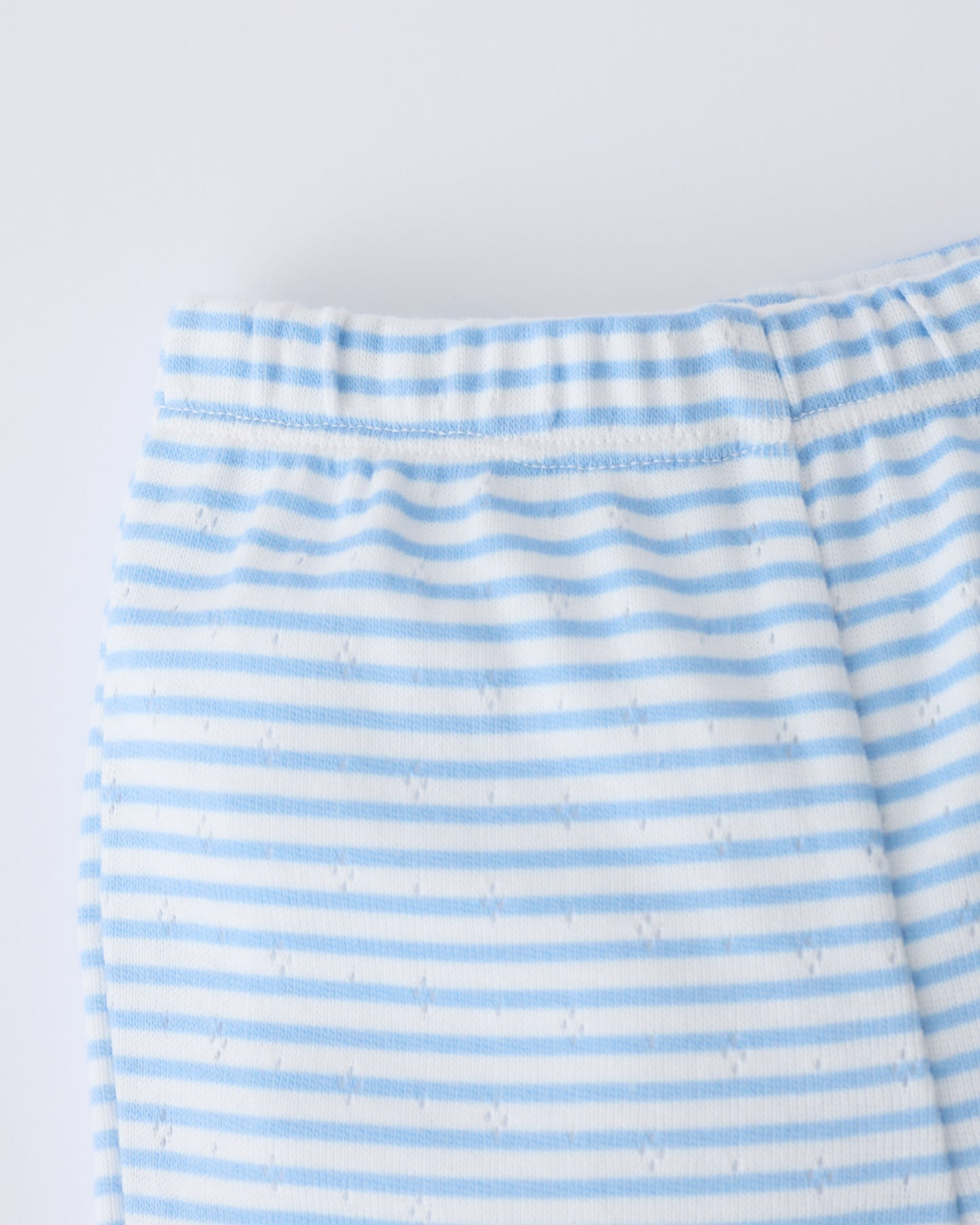 Close up of the waistband of the Pointelle Leggings in Blue Candy Stripe on a beige background.