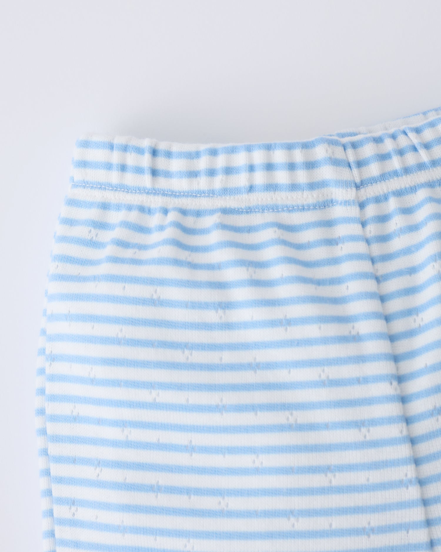 Close up of the waistband of the Pointelle Leggings in Blue Candy Stripe on a beige background.