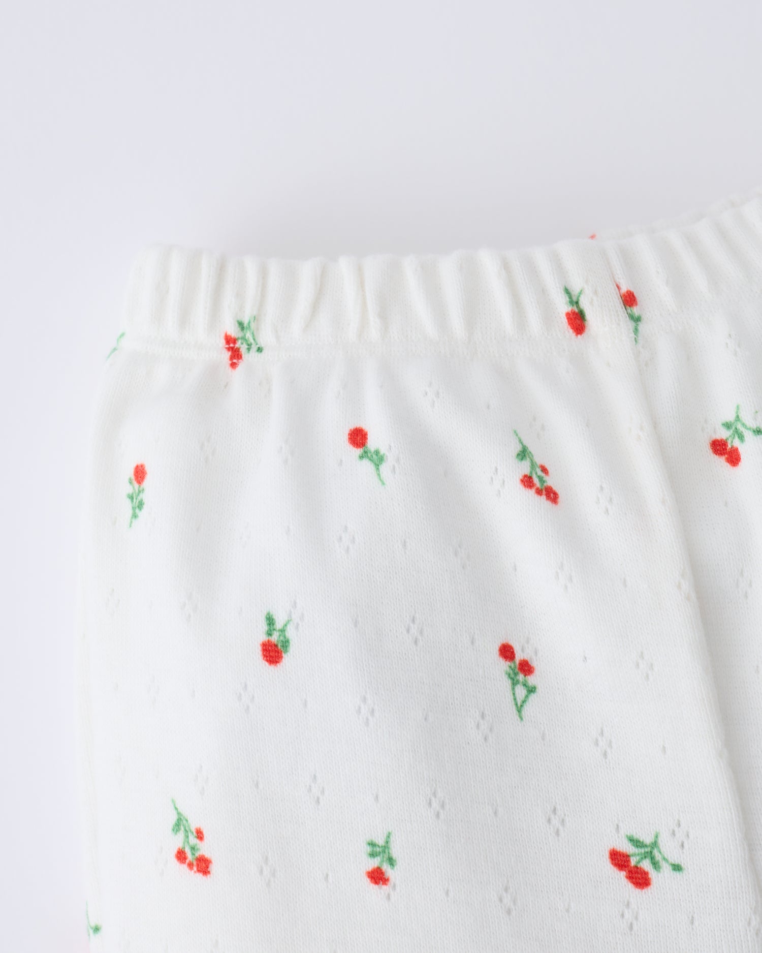 Close up of the waistband on the Pointelle Leggings in Dainty Ditsy pattern on a beige background.
