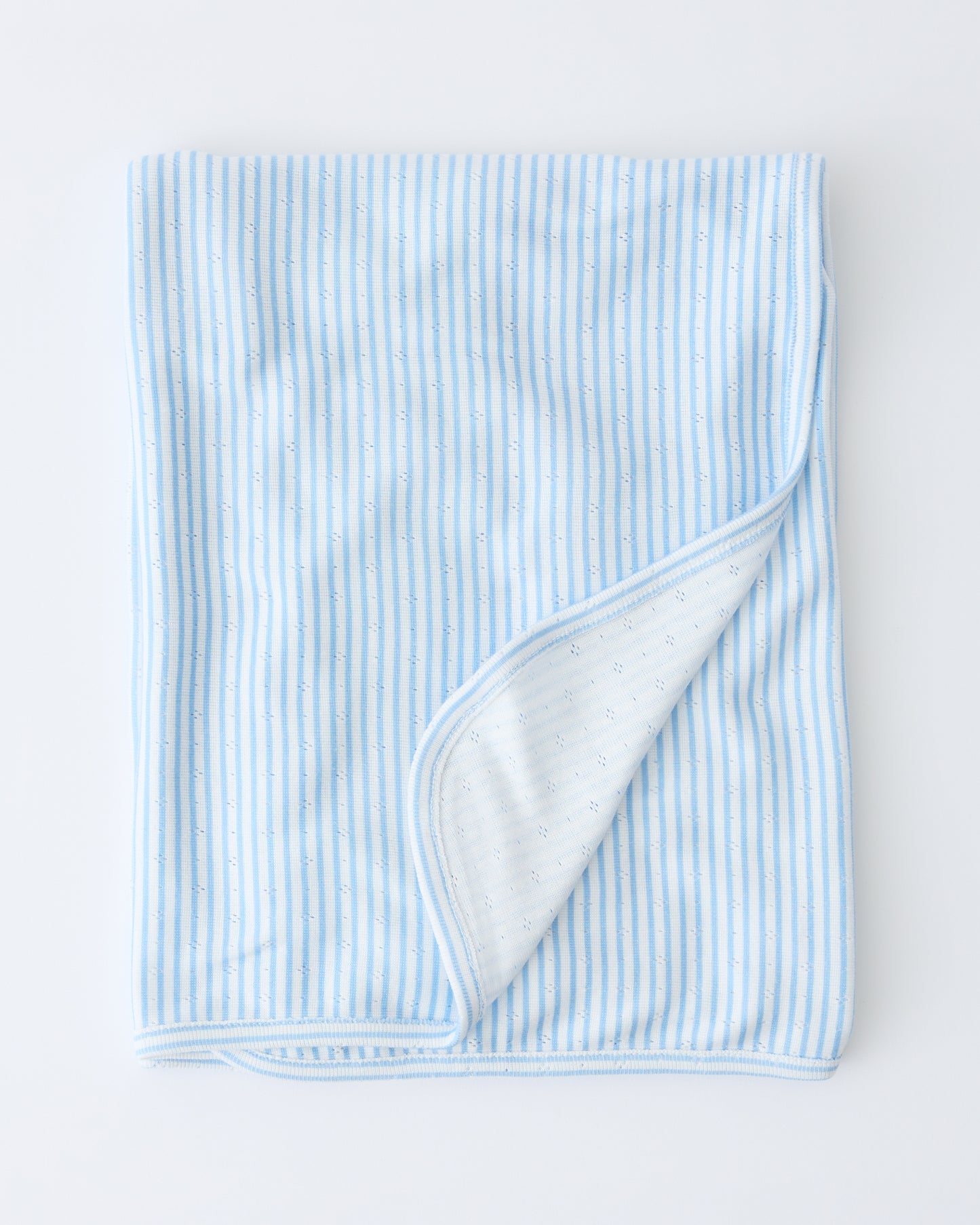 Pointelle Swaddle in Blue Candy Stripe folded with a flipped corner to show reverse side, on a beige background.