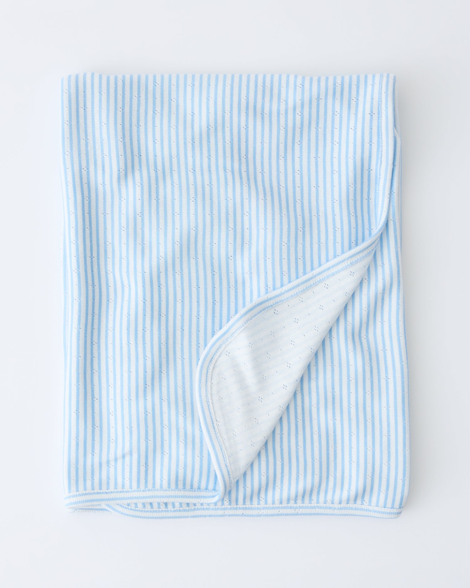 Pointelle Swaddle in Blue Candy Stripe folded with a flipped corner to show reverse side, on a beige background.