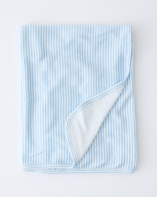 Pointelle Swaddle in Blue Candy Stripe folded with a flipped corner to show reverse side, on a beige background.