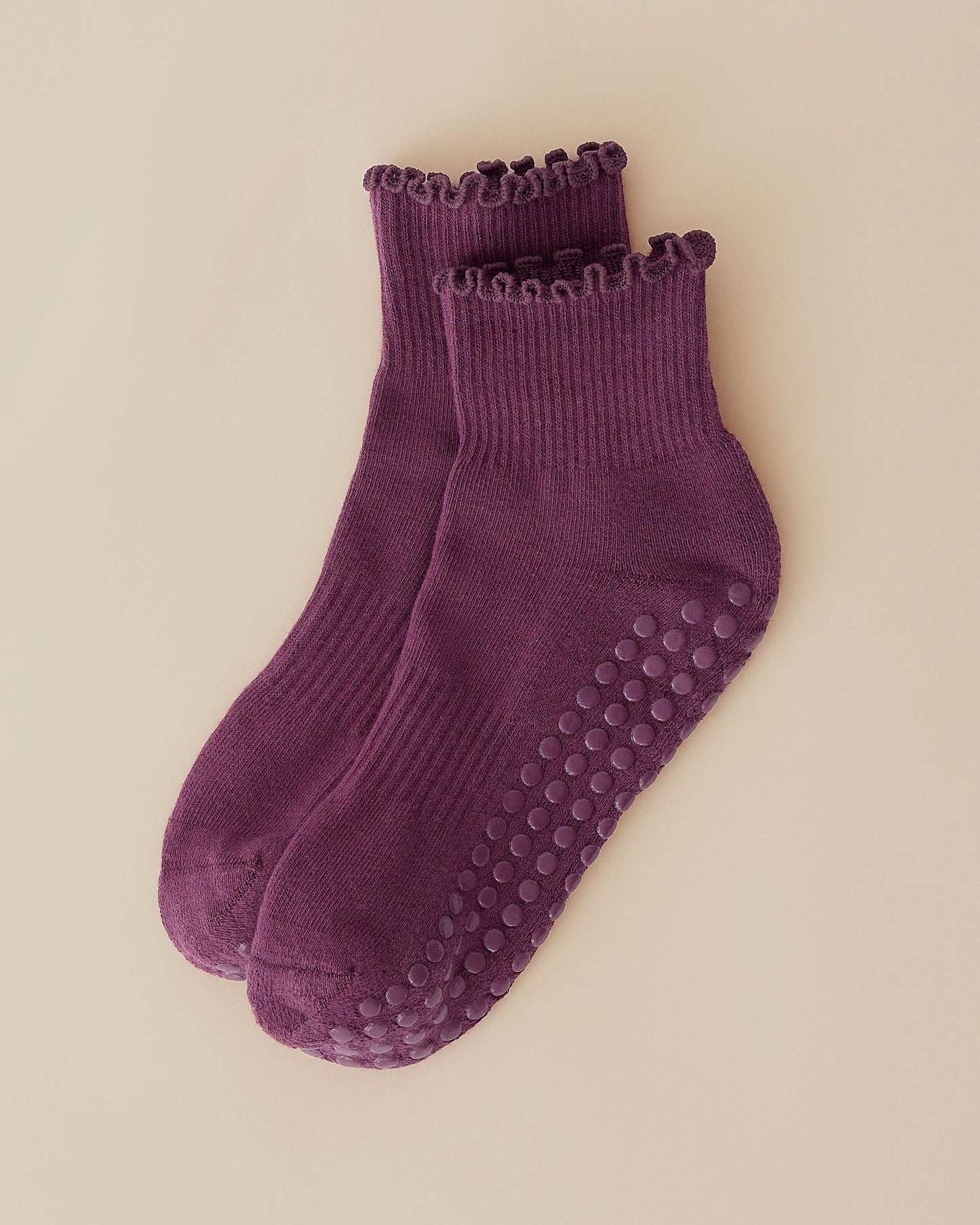 A pair of Non-Slip Ruffle Ankle Socks in Burgundy Plum on a beige background.