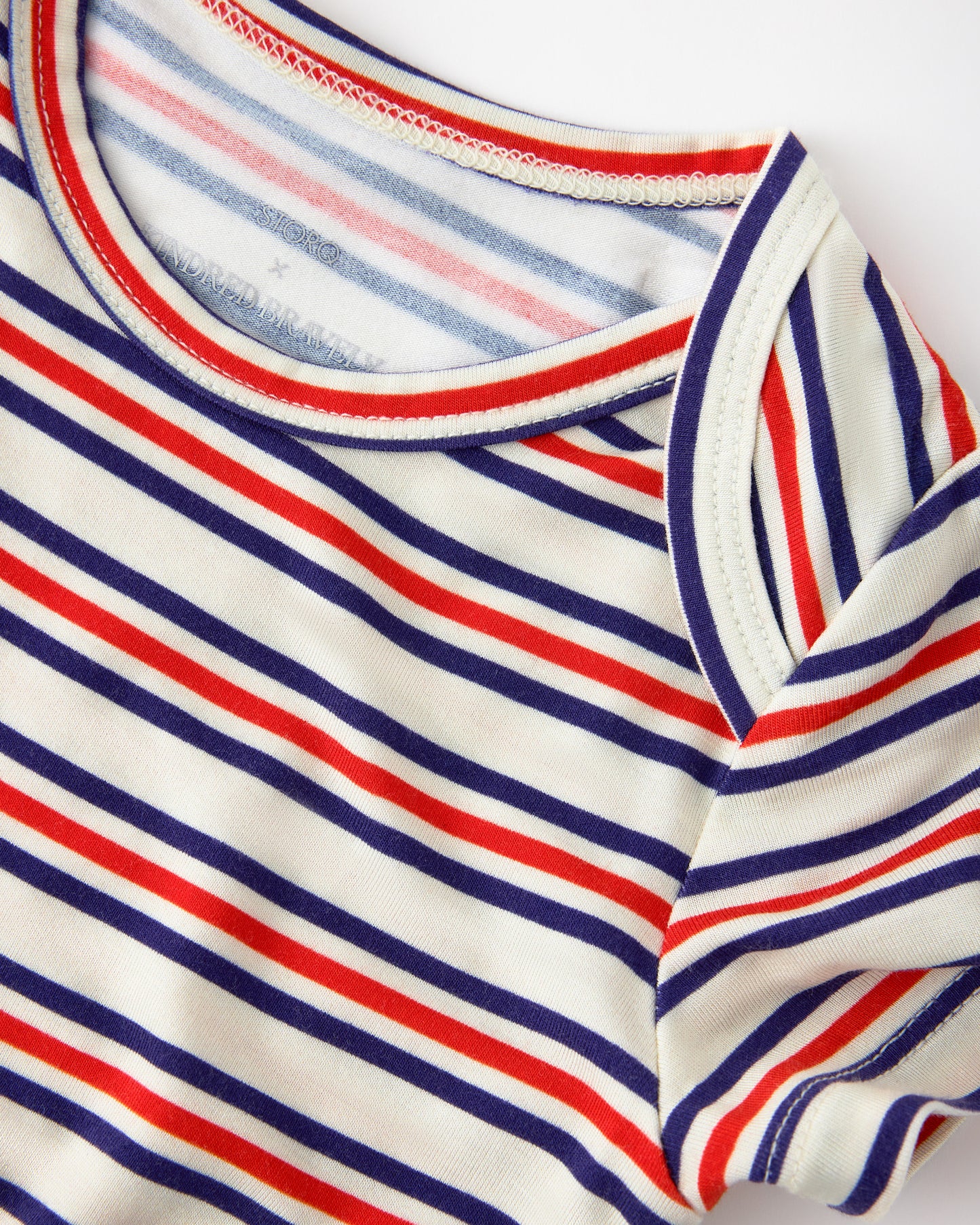 Close up of collar detail on Baby Onesie Two-Pack in Red & Blue Stripe on a beige background