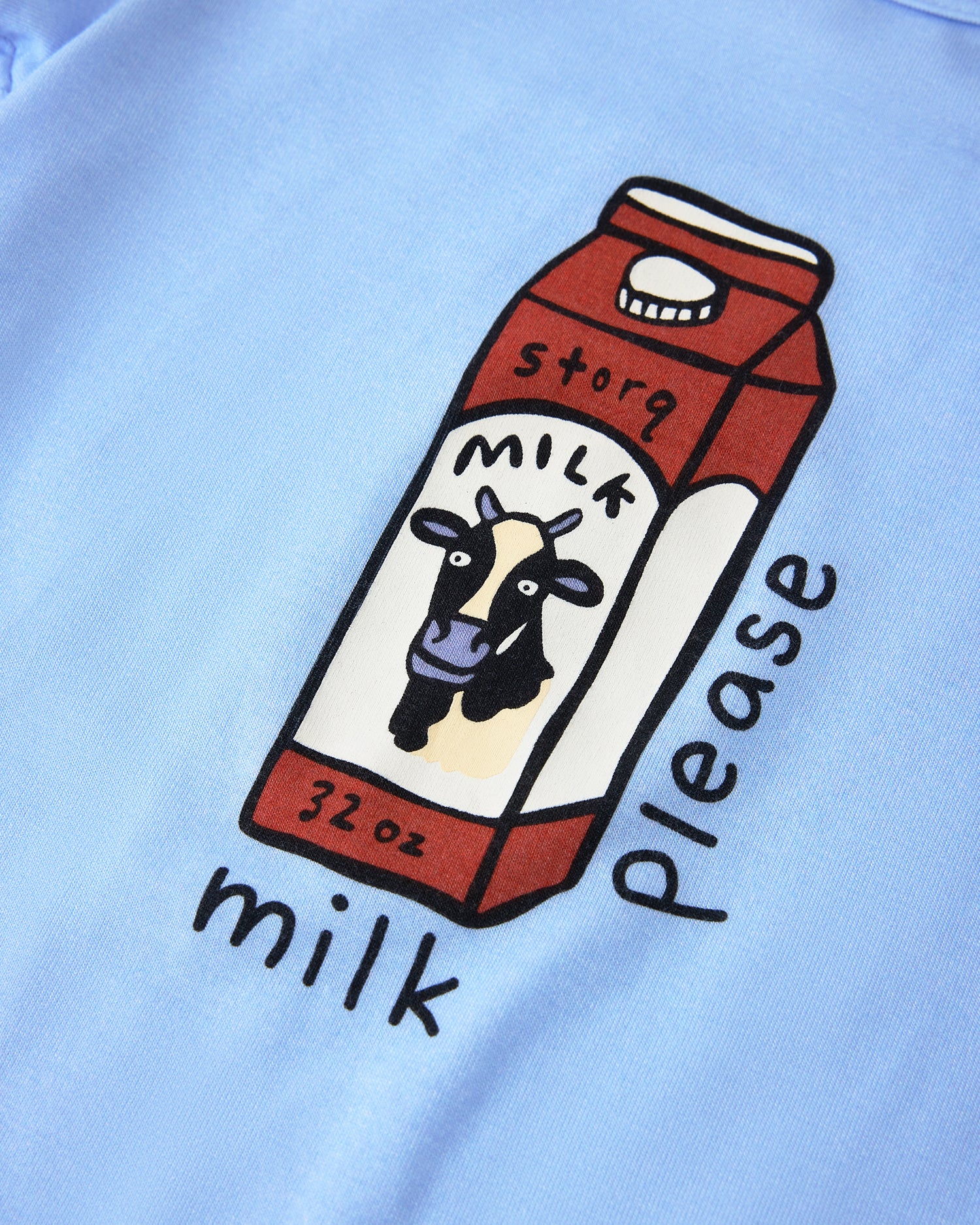 Close up of graphic on Baby Onesie Two-Pack in Milk Please on a beige background