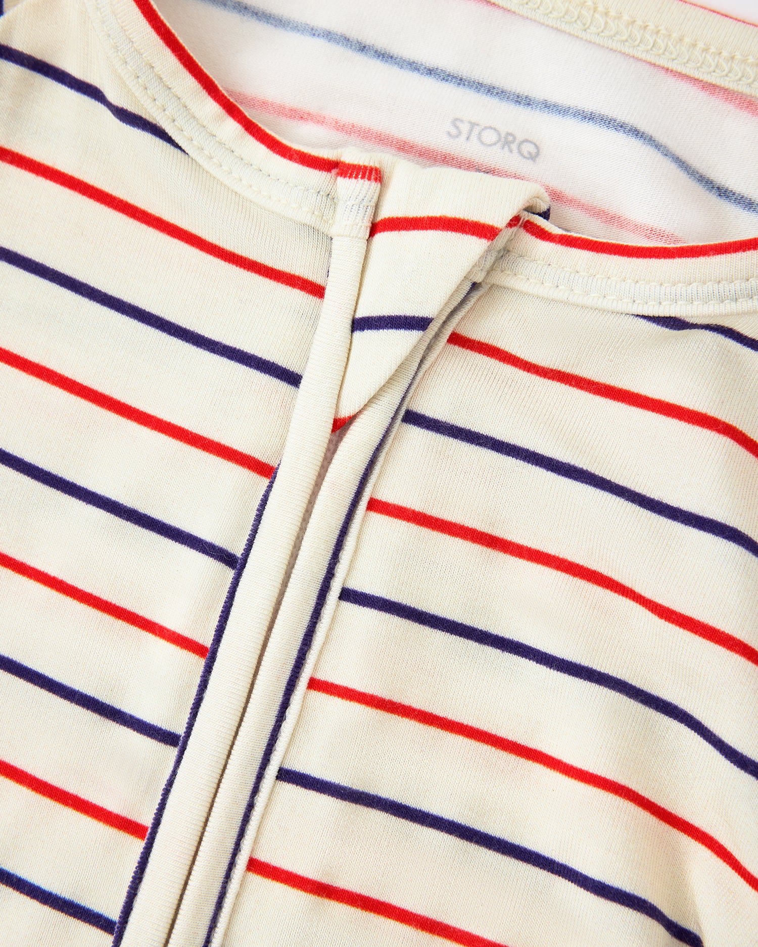 Close up zipper and collar detail of Bamboo Baby Pajama in Pencil Stripe on a beige background