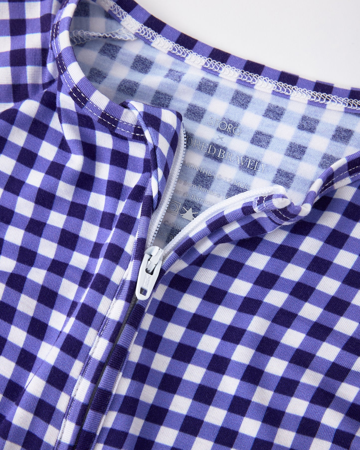 Close up detail of collar and zipper of the Bamboo Baby Pajama in Blue Gingham on a beige background