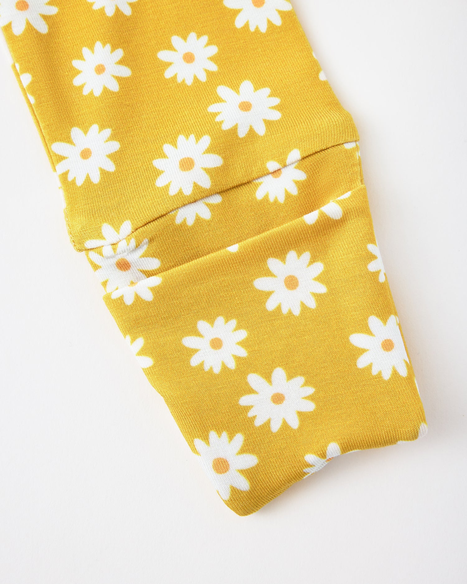 Close up of sleeve detail of Bamboo Baby Pajama in Yellow Daisies on a beige background