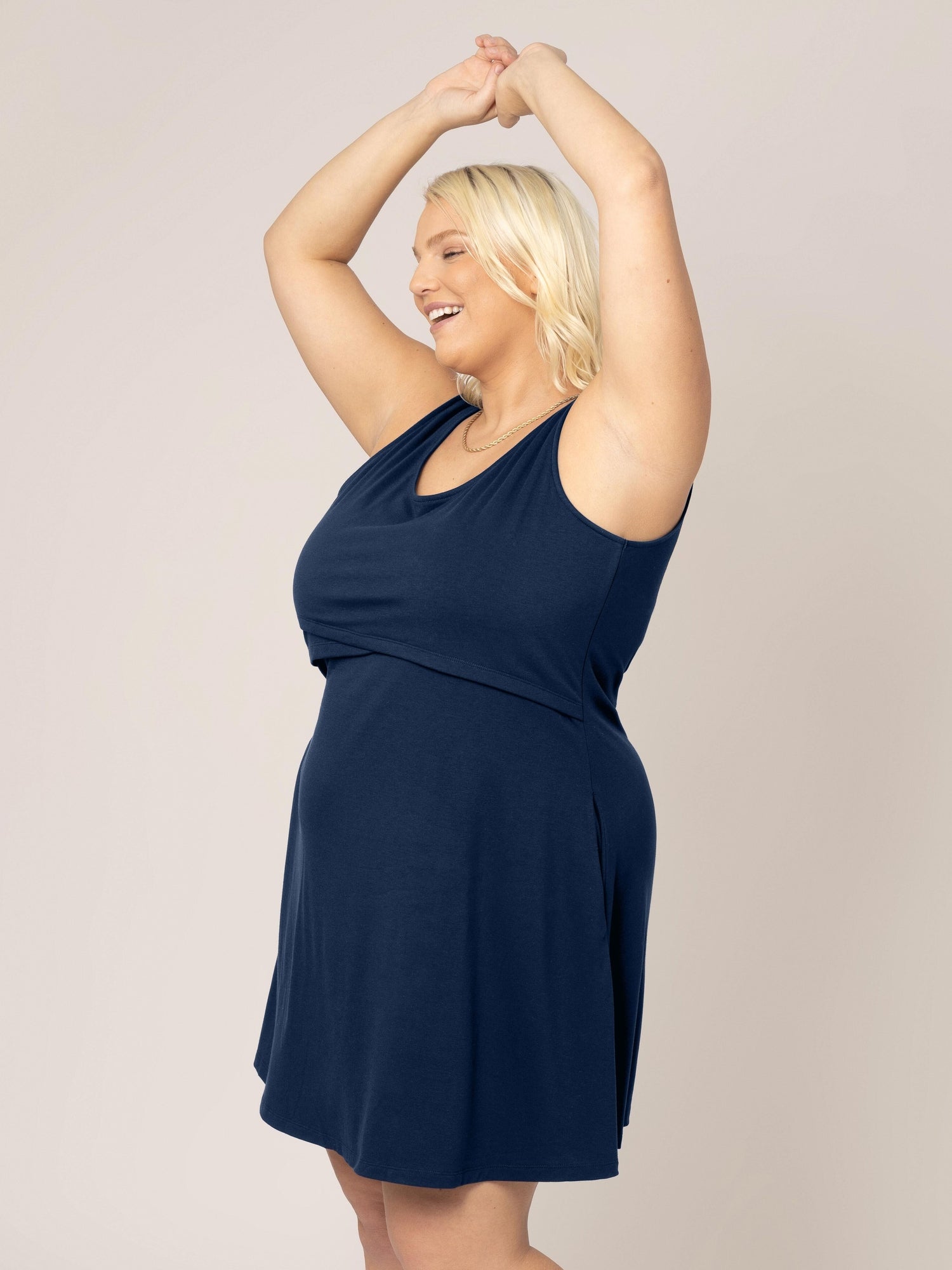 Side view of model with arms in the air wearing the Penelope Crossover Nursing Dress in navy