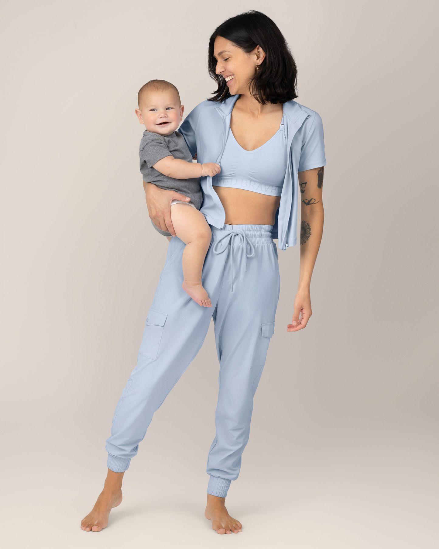 Front view of Model holding a baby while wearing the Remy Maternity & Postpartum Cargo Jogger in French Blue with matching Presley Active Zip Front Nursing Top @model_info:Megan is 5'7" and wearing a Small.