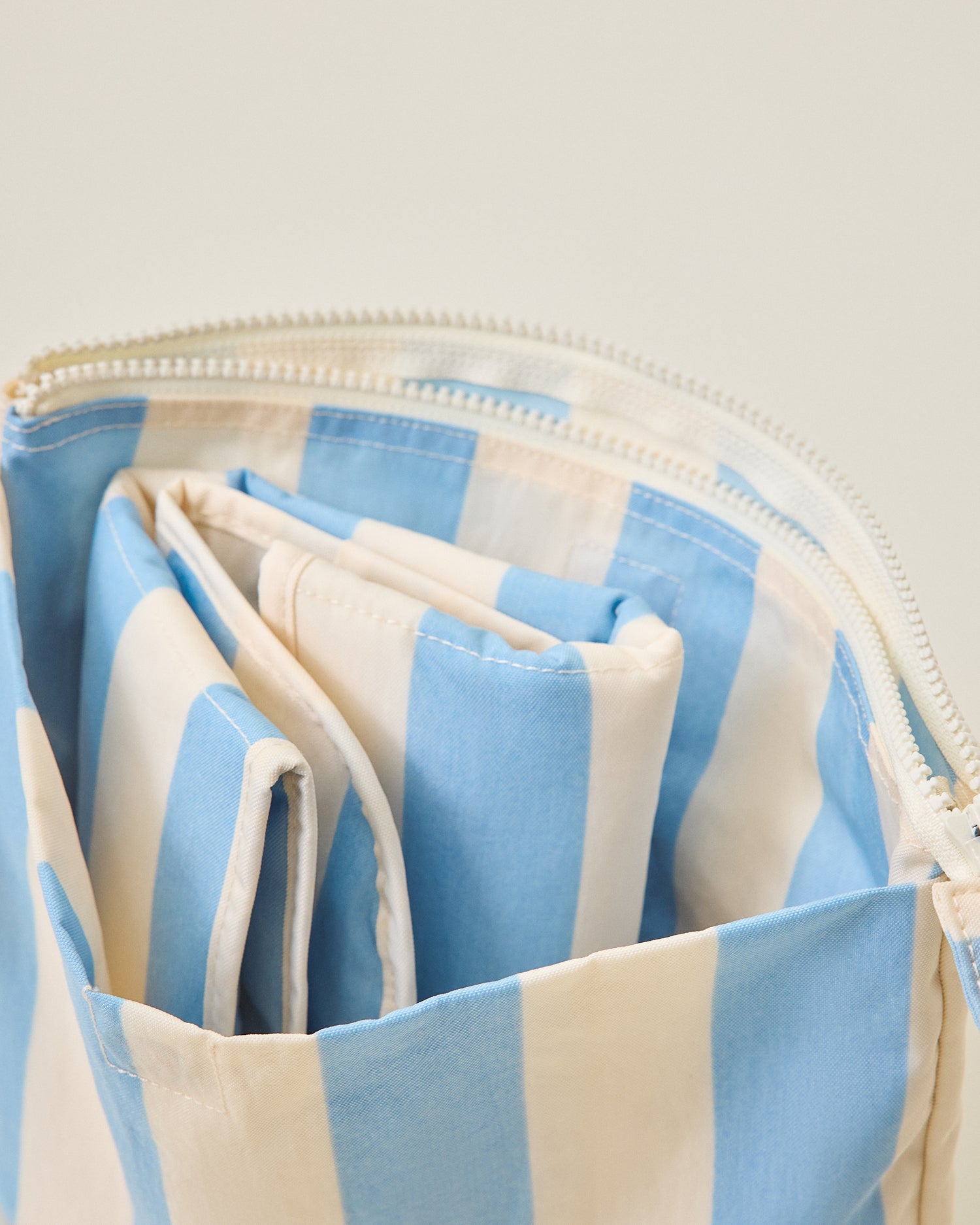 Zipper pouch with changing pad in blue and off-white wide striped pattern on a light background