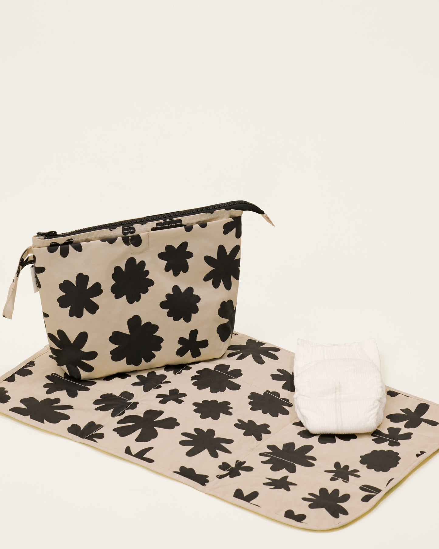 Quick Change Kit Bag in Cream Chamomiles print, on a neutral background, with the included changing pad open under it