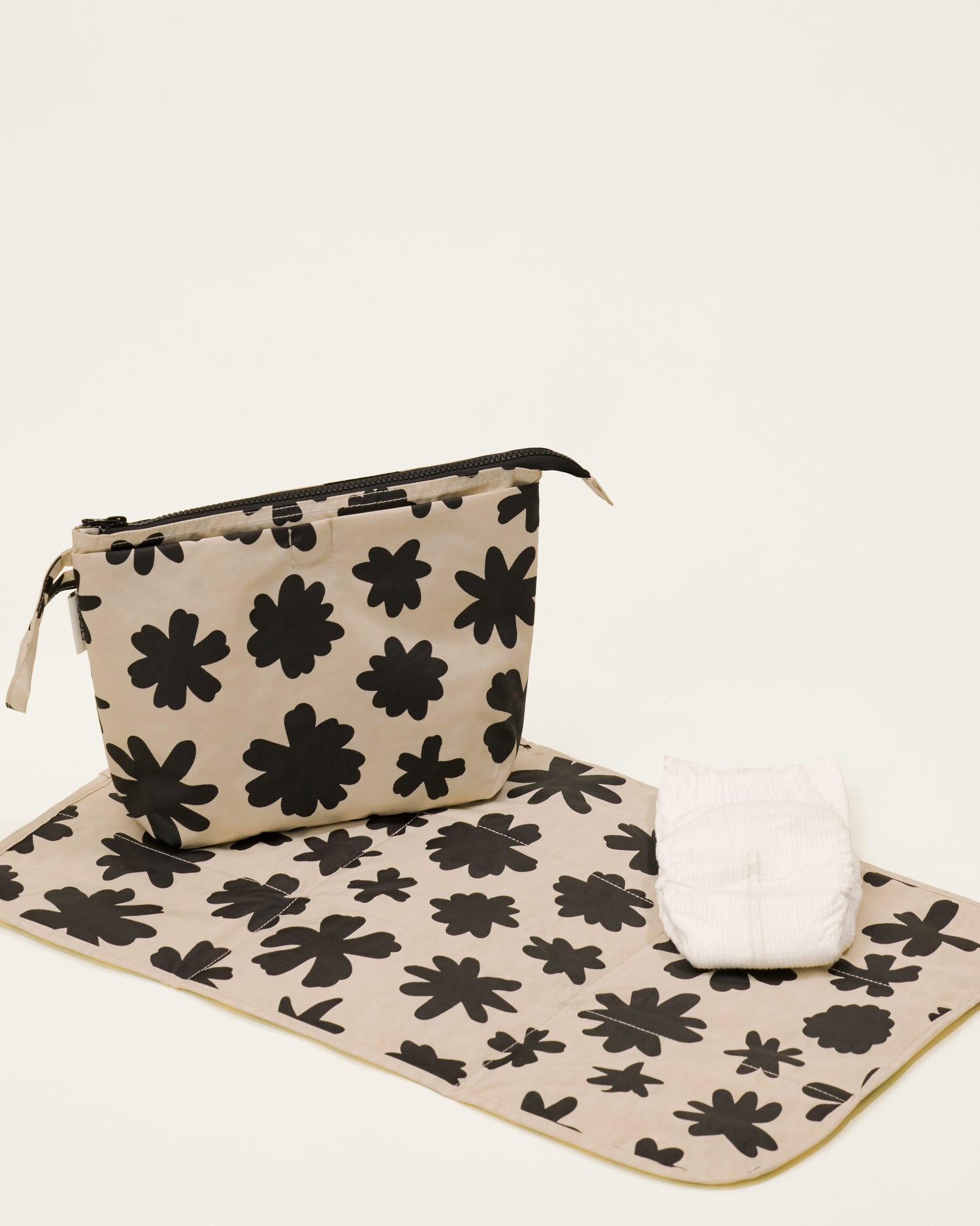 Quick Change Kit Bag in Cream Chamomiles print, on a neutral background, with the included changing pad open under it