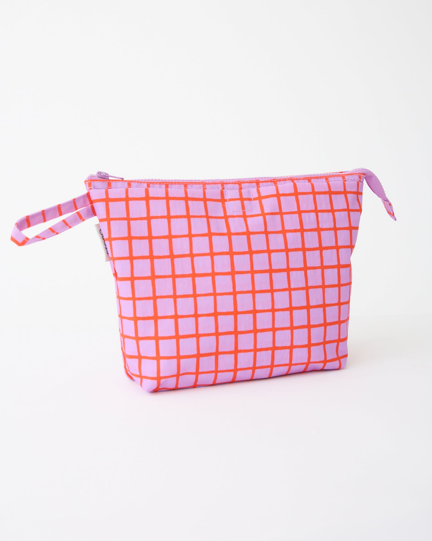 Quick Change Kit Bag in Orchid Grid, on a beige background.