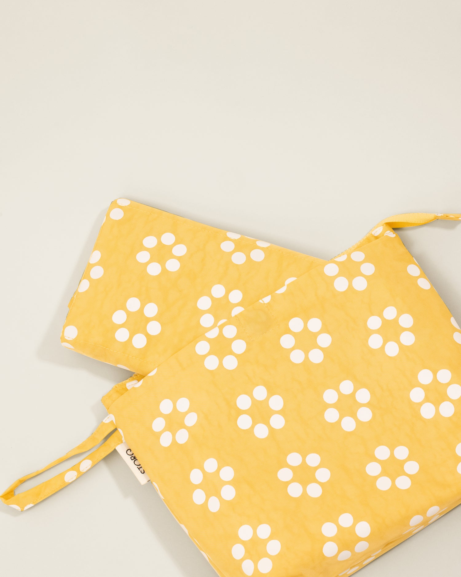 Quick Change Kit Bag in Sunshine Dots print, on a neutral background and showing the folded changing pad