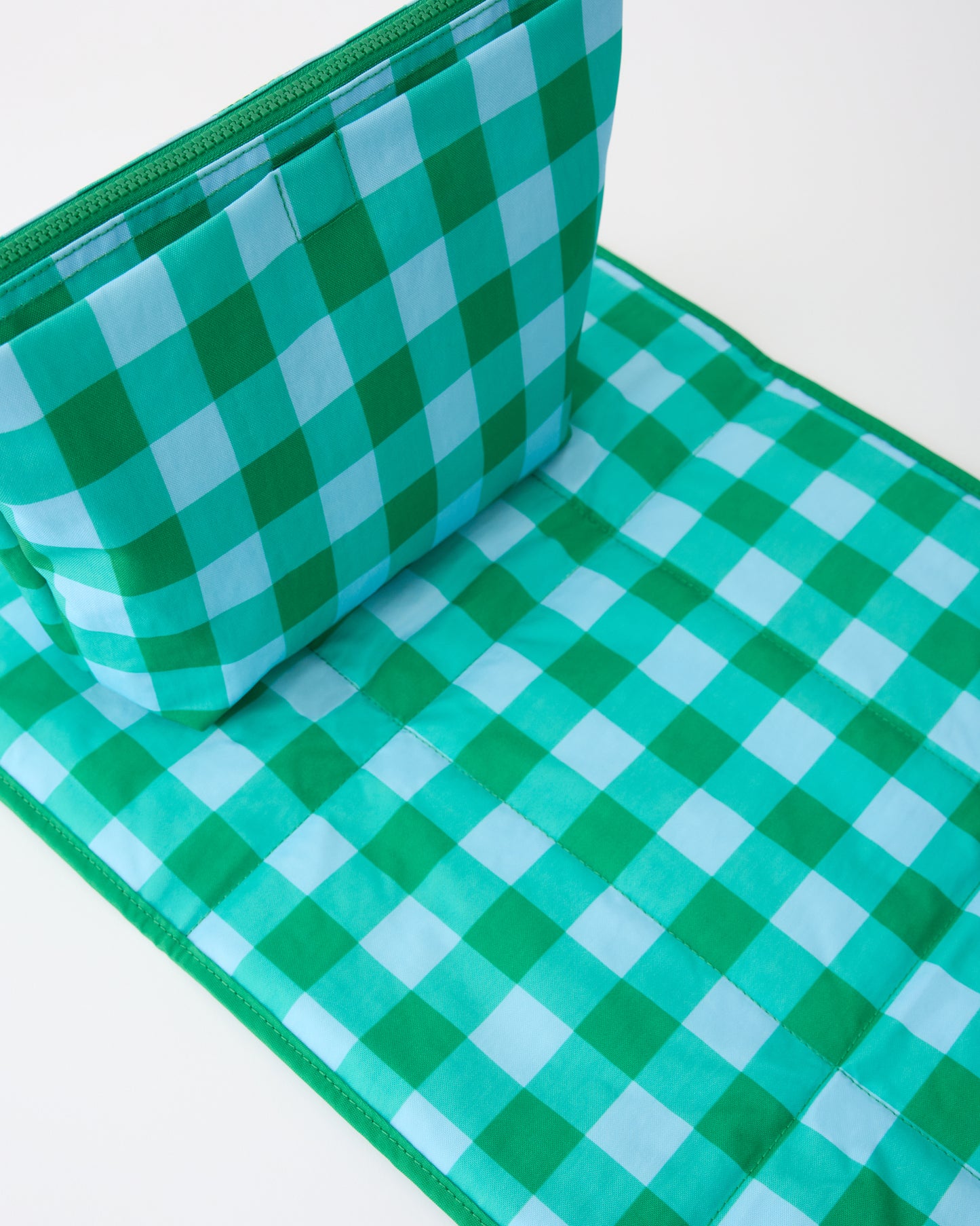 Quick Change Kit Bag in Teal Gingham, resting on matching changing mat, on a beige background.