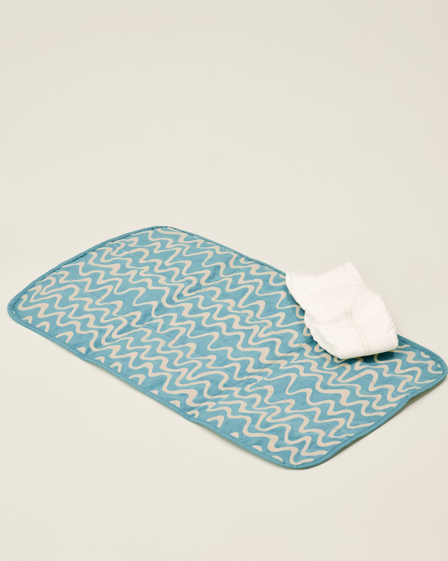 Changing pad of the Quick Change Kit Bag in Blue Waves print shown open with a nappy