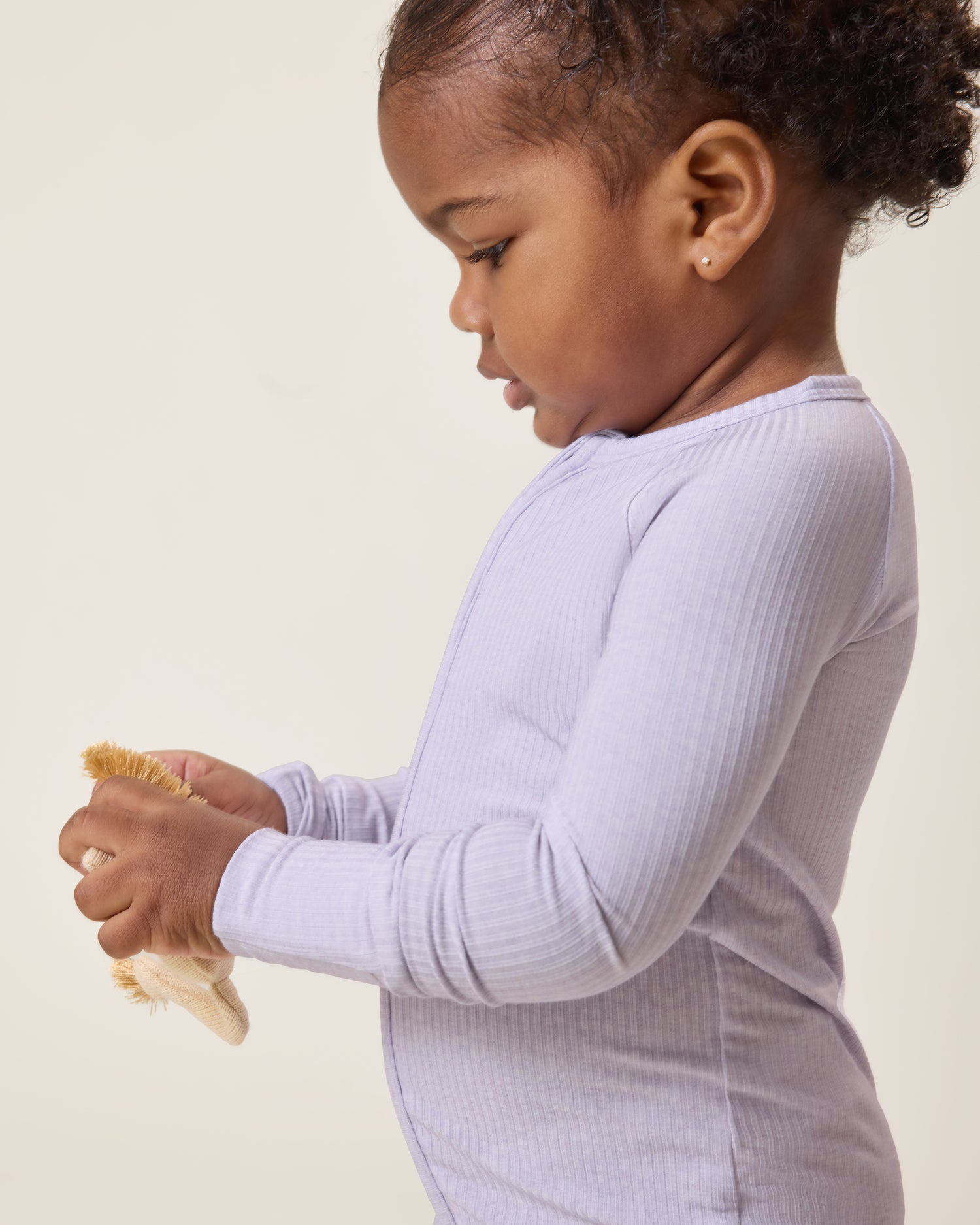 Baby looking down wearing the Ribbed Bamboo Baby Pajama in Lilac Heather