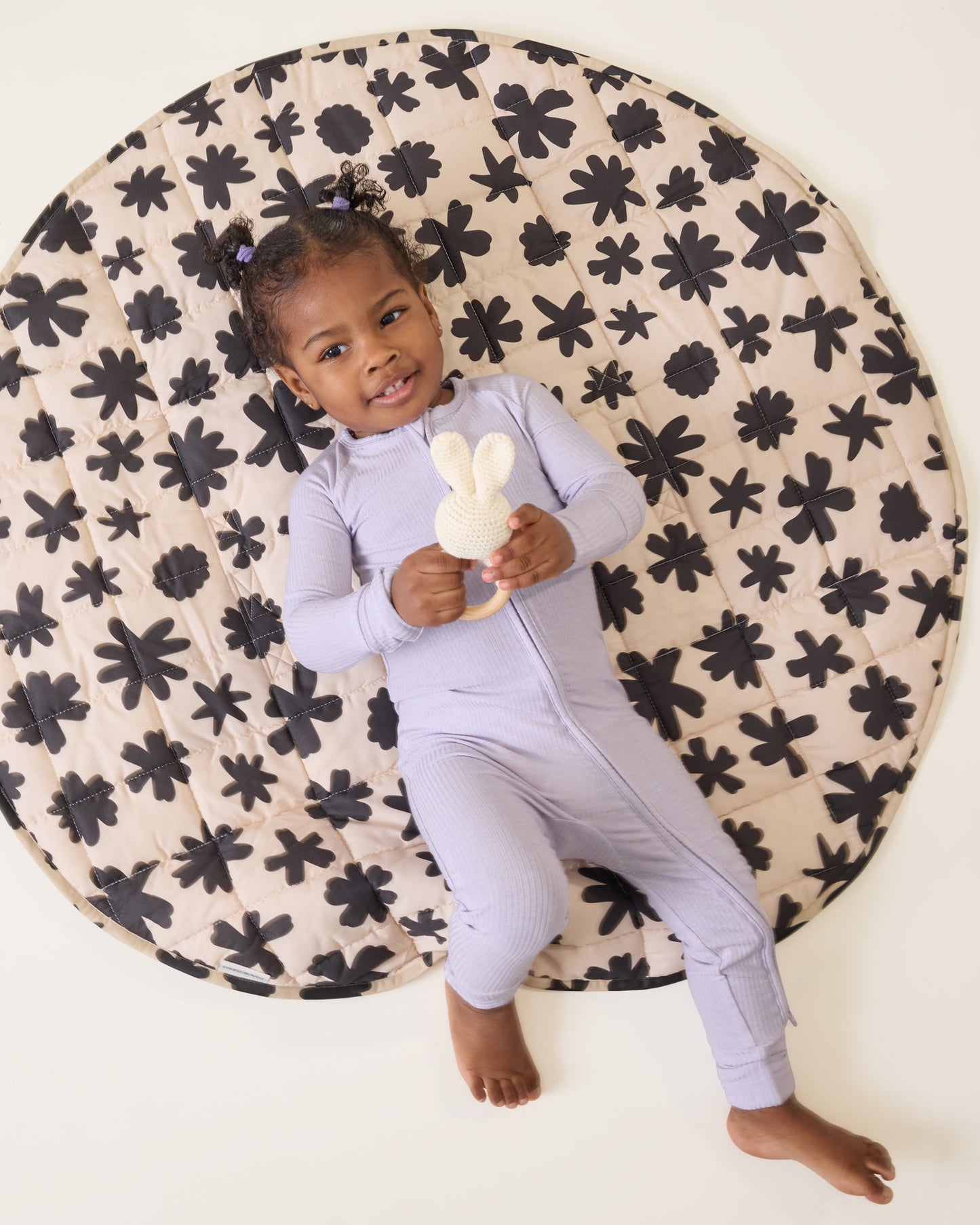 Child laying on the Inside/Outside Play Mat in Cream Chamomiles print
