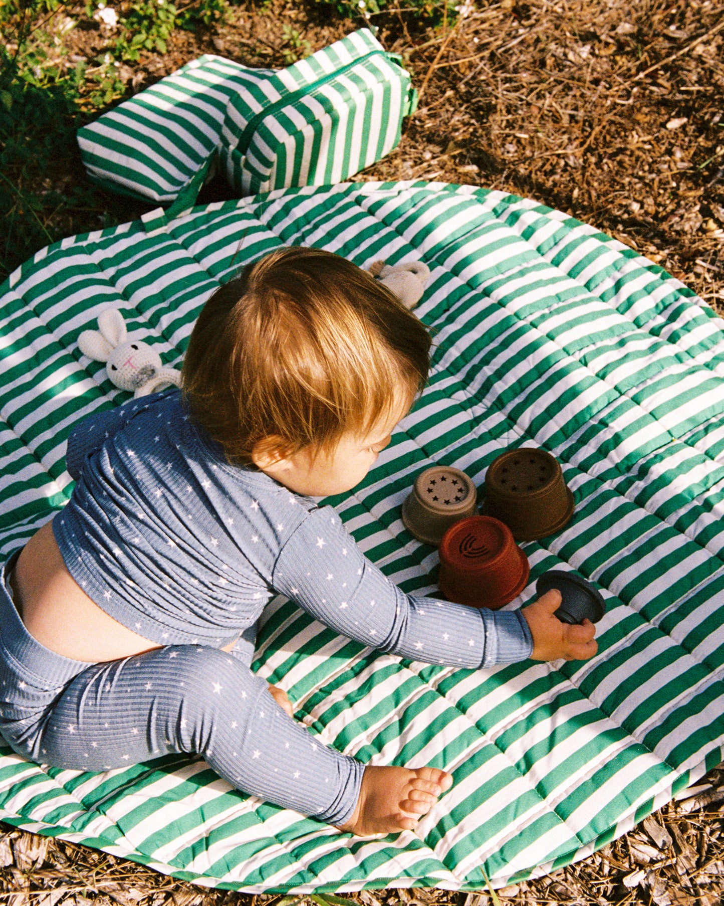 Child playing on the The Inside/Outside Play Mat in Green Stripe print outdoors