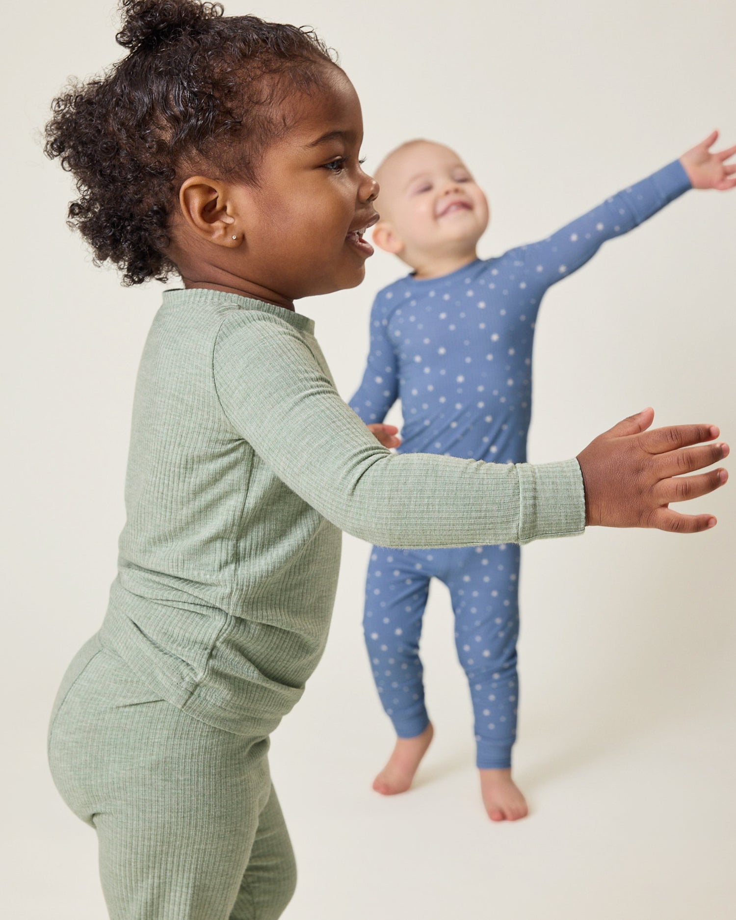Two children wearing ribbed pajamas on a plain background