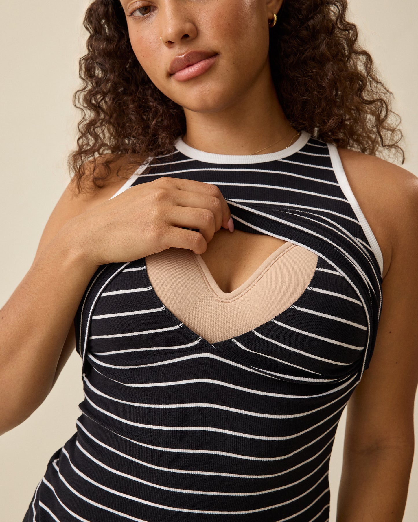 Model lifting front panel for breastfeeding access of Ribbed Bamboo Scoop Neck Nursing Tank in Black White Stripe on a beige background