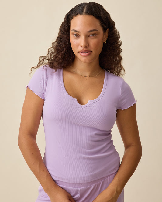 Model wearing Ribbed Modal Notched Nursing T-Shirt in Lavender on a beige background.@model_info:Mei is wearing a Small.