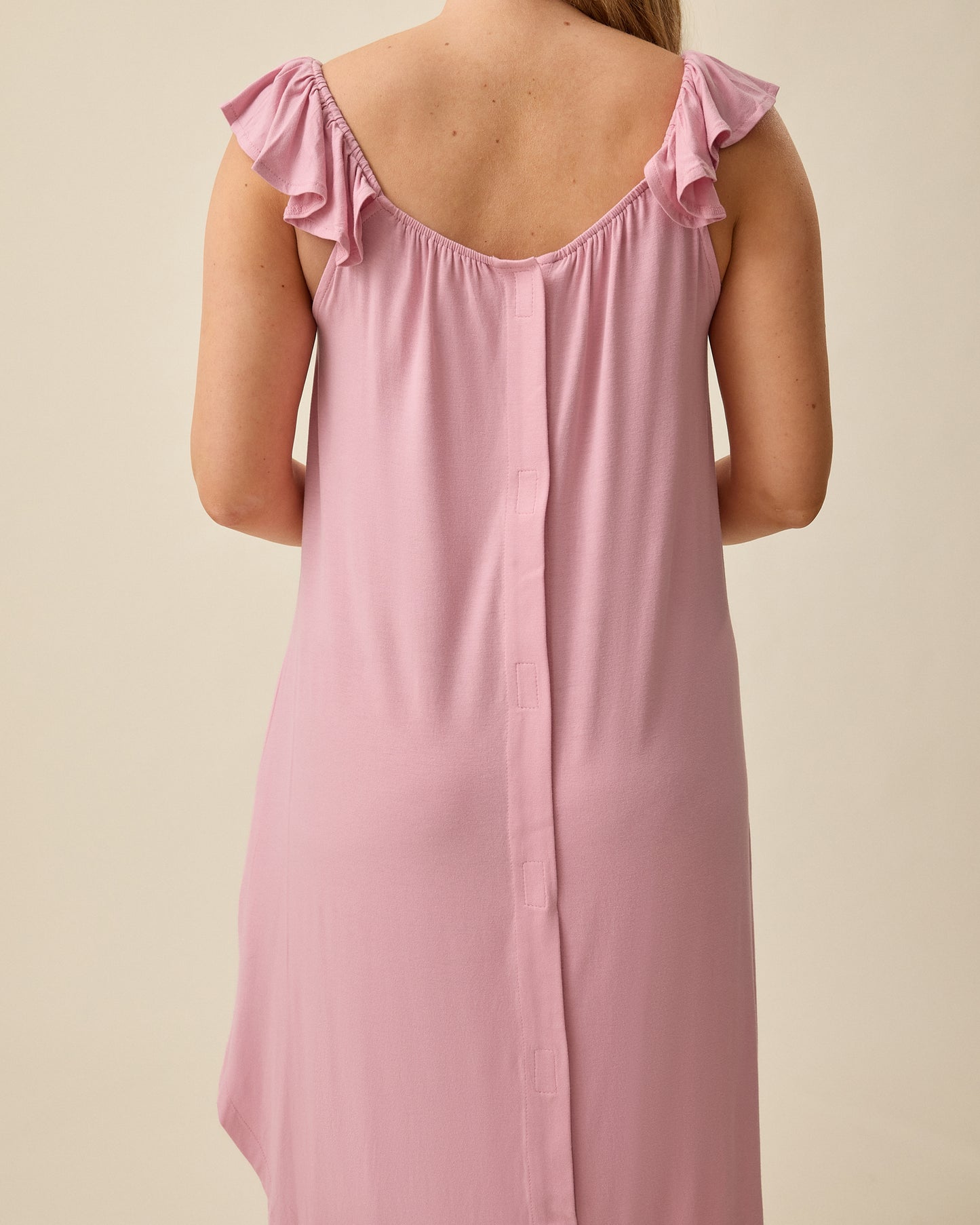 Back view of model wearing Ruffle Strap Labor & Delivery Gown in Light Mauve on a beige background