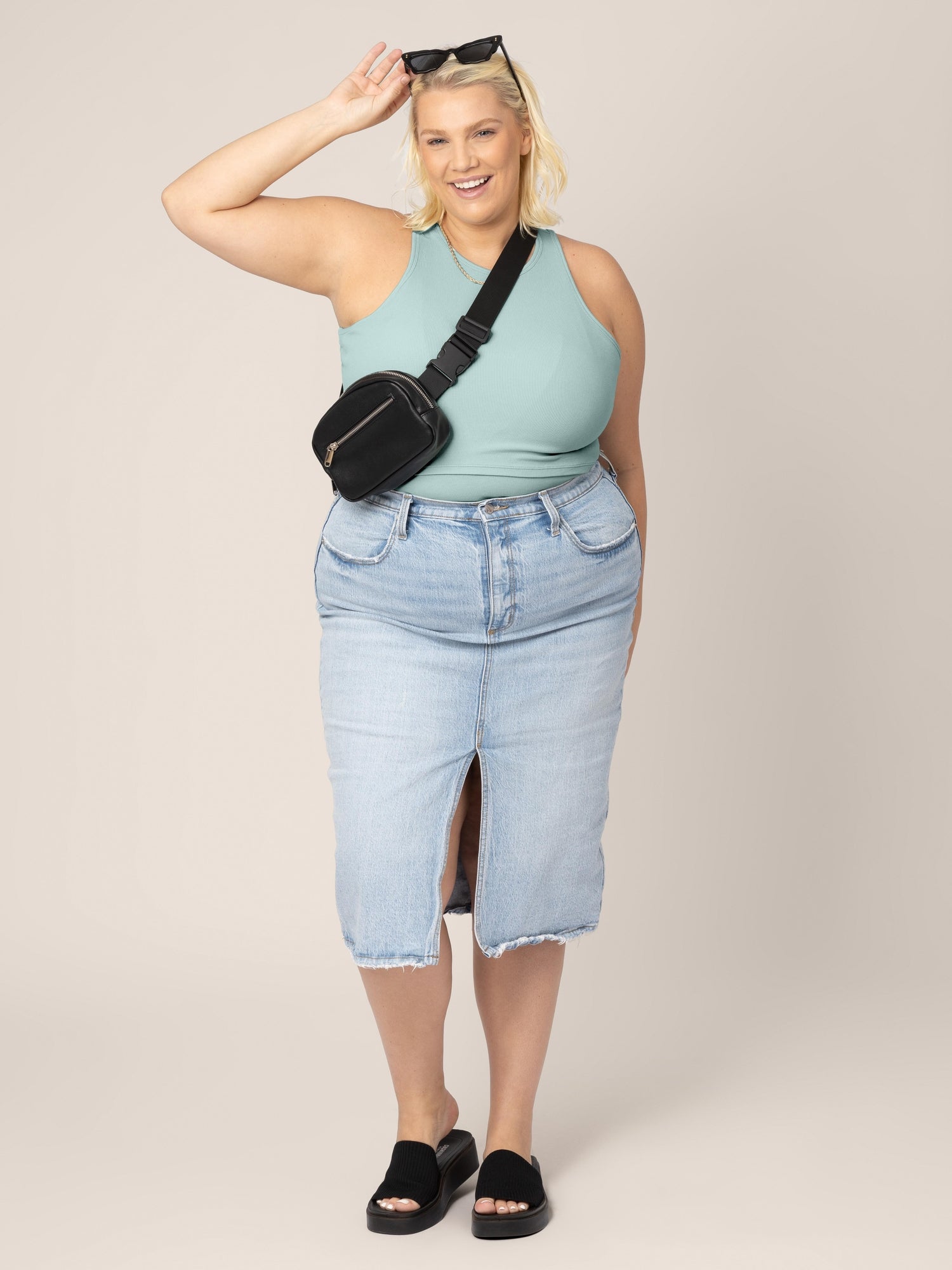 Model in the Ribbed Bamboo Racerback Nursing Tank in dusty blue green, paired with jean skirt, sandals, cross-body belt bag and sunglasses