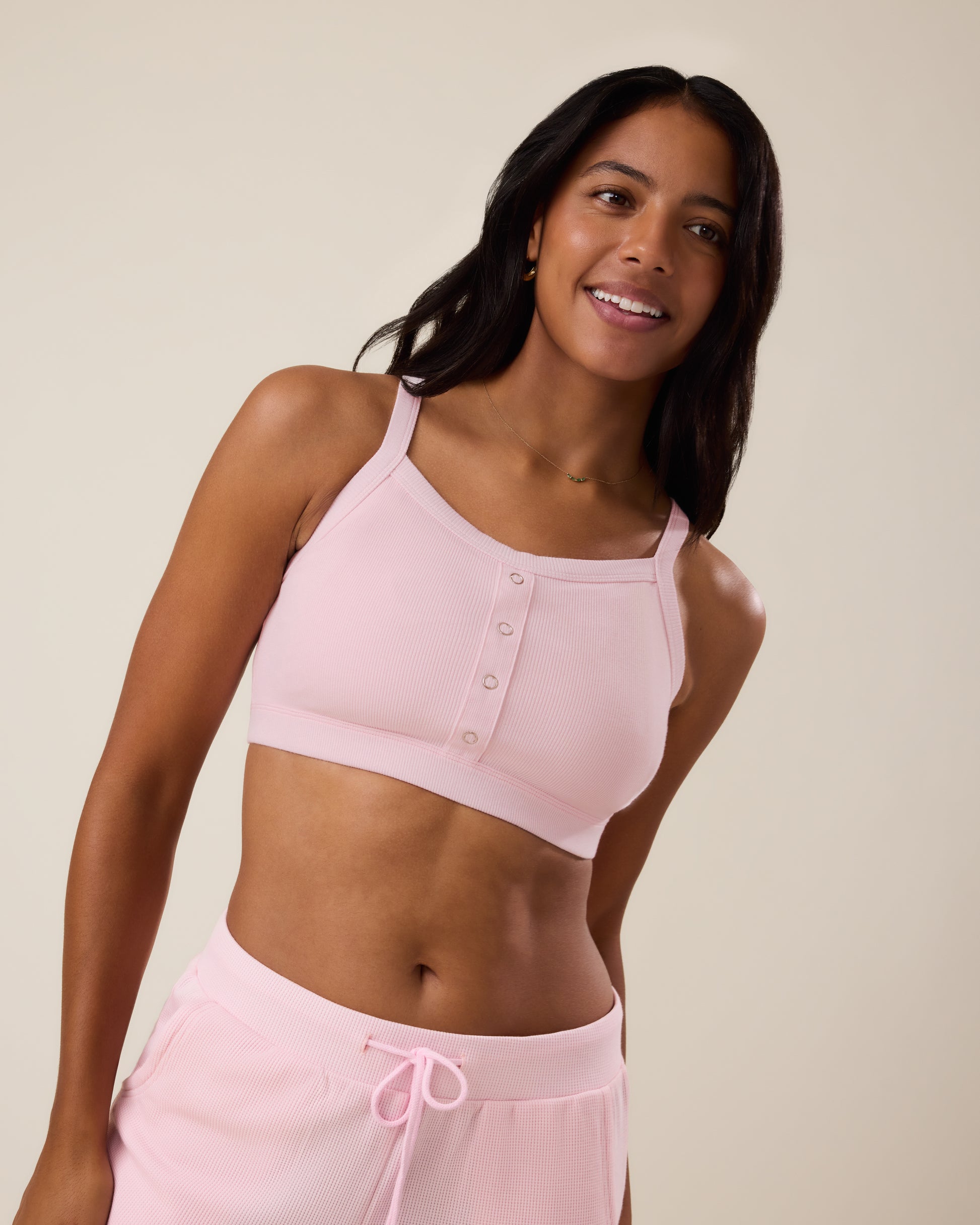 Woman wearing the Ribbed Bamboo Pumping Bralette in Pale Pink with matching bottoms@model_info:Nemesis is wearing a Medium.