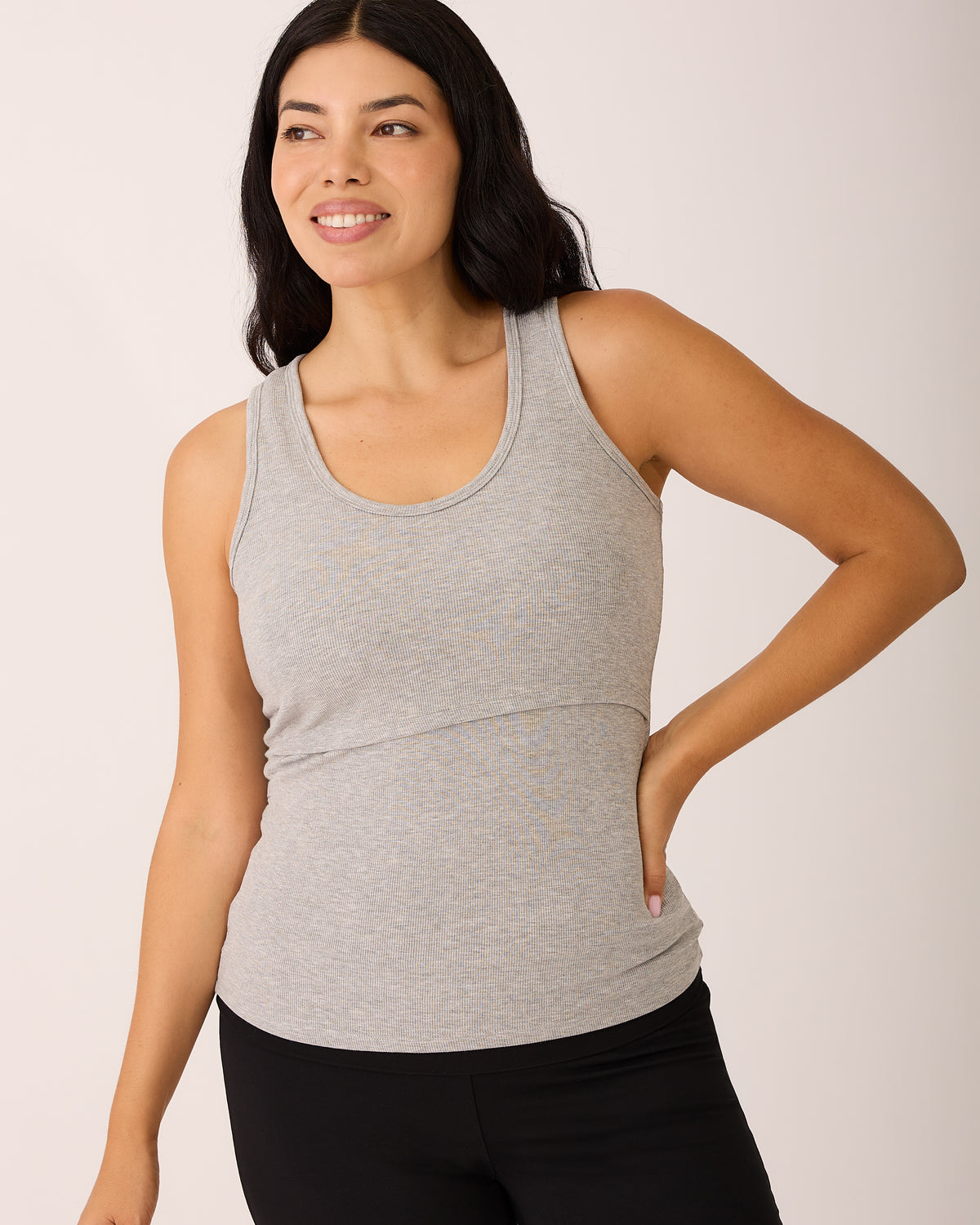 Model is wearing Ribbed Bamboo Scoop Neck Nursing Tank in Grey Heather with Bamboo Flex Maternity & Postpartum Flare Pant in Black, on a beige background. @model_info:Ashley is wearing a Medium.