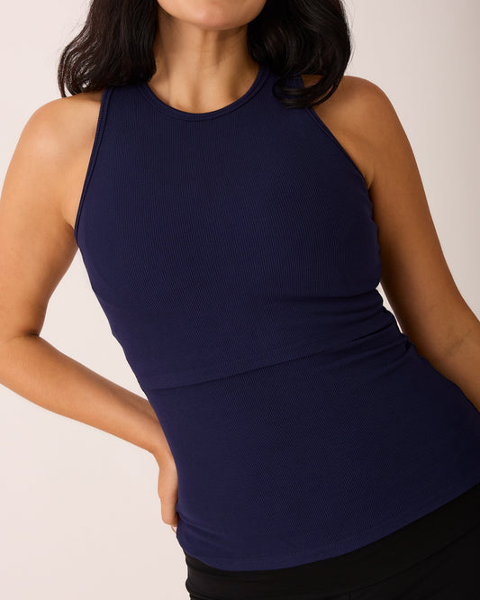 Model is wearing Ribbed Bamboo Racerback Nursing Tank in Navy on a beige background.@model_info:Ashley is wearing a Medium.