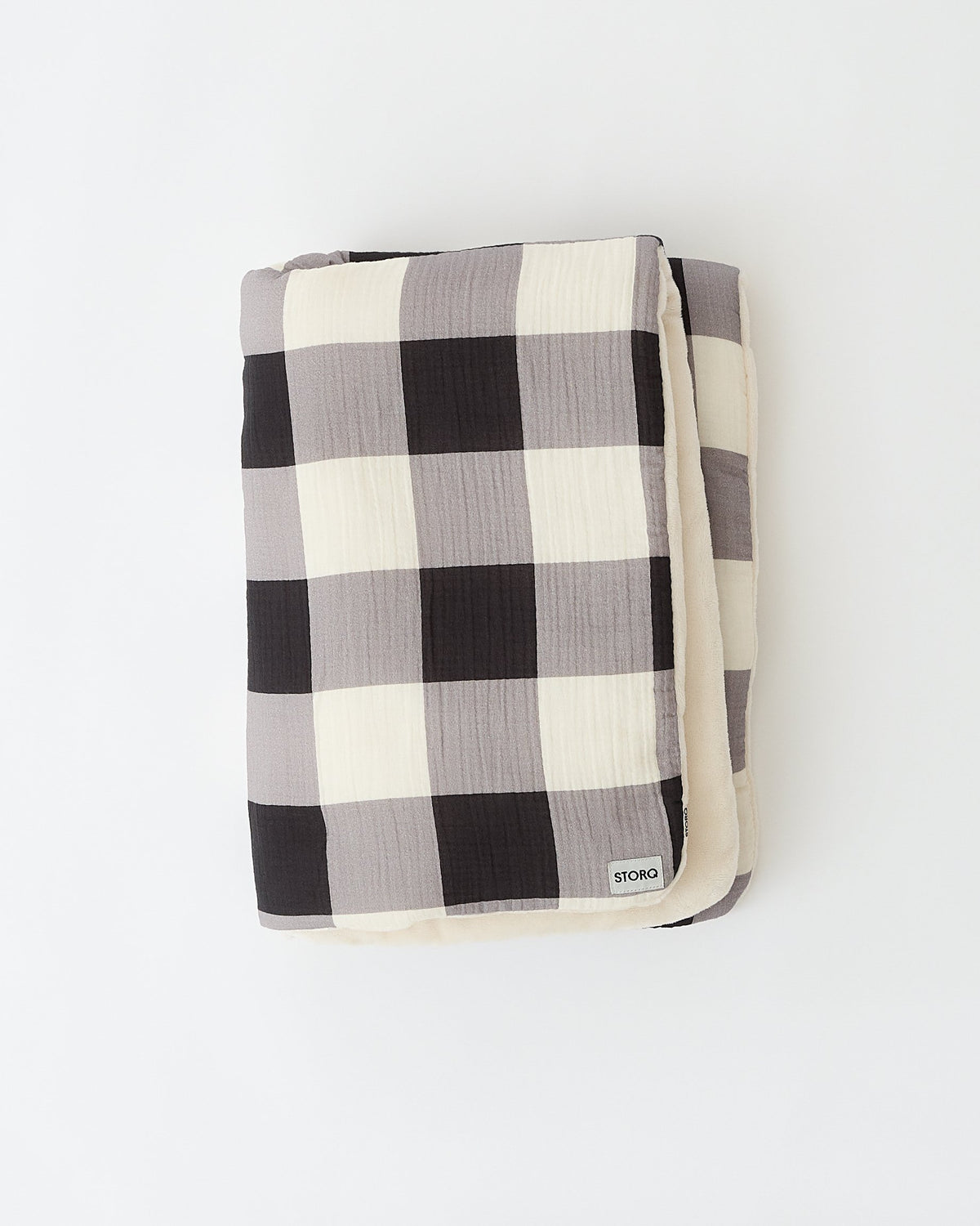 Folded up Cozy Stroller Blanket in Buffalo Plaid, showing pattern on one side and fuzzy soft material on the other side, on an off white background.