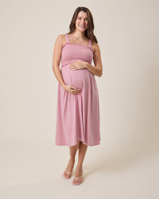 Pregnant woman wearing a pink dress against a beige background@model_info:Elliana is 5'7" and wearing a Medium.