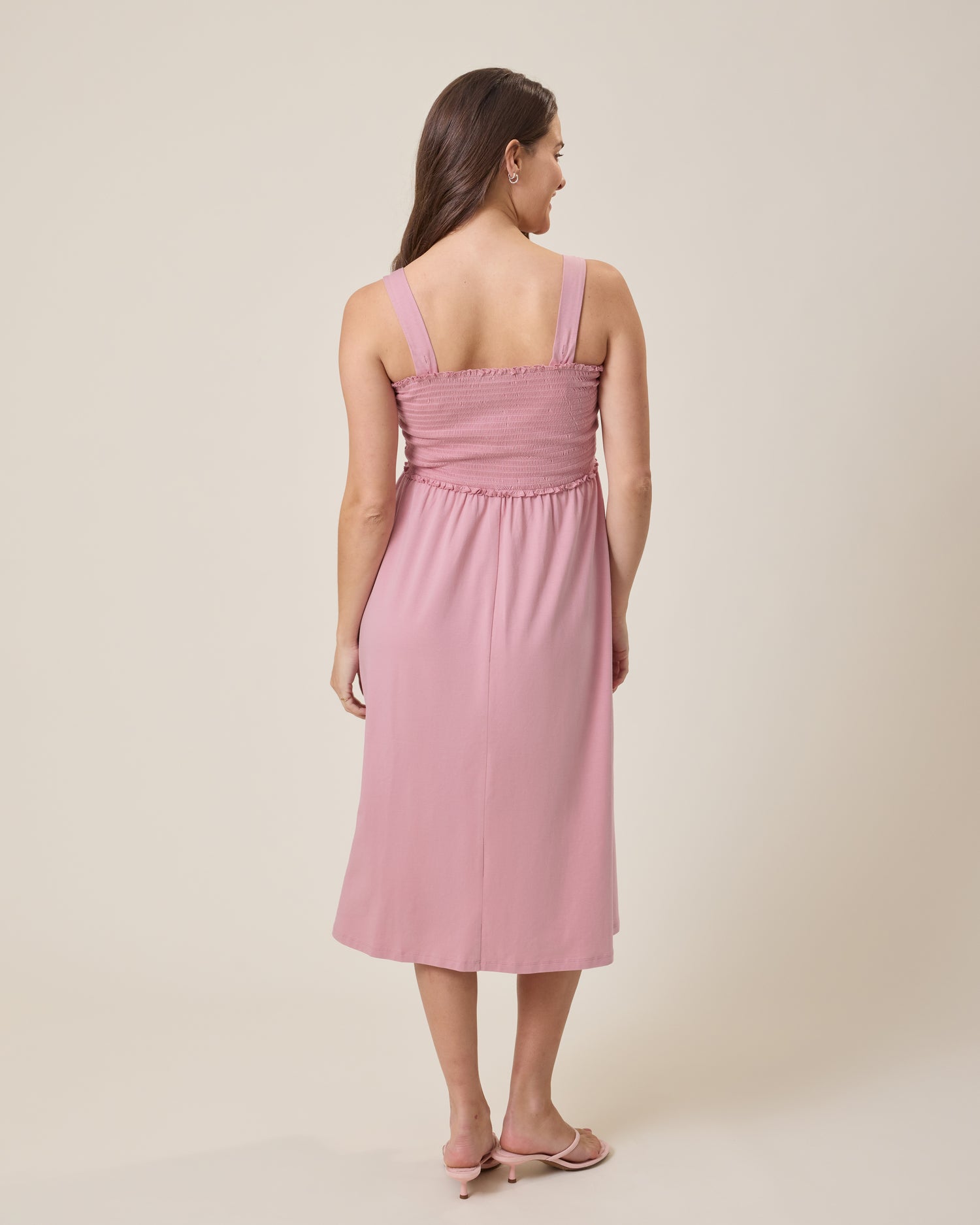 Woman wearing a pink dress against a beige background