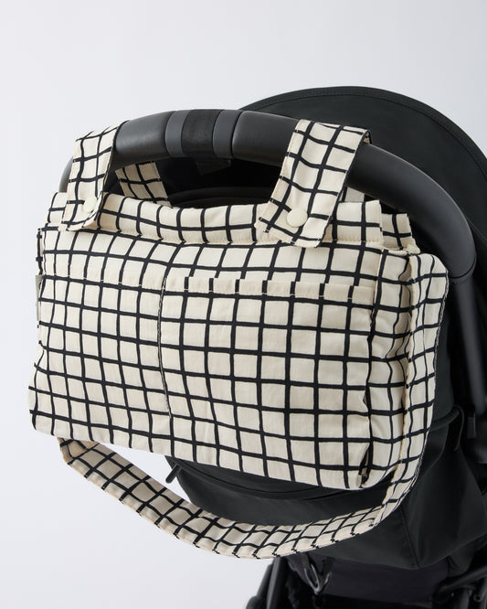 Black Stroller with Stroller Party™ Caddy Bag in Black Grid clipped onto the handle bar, on a beige background.