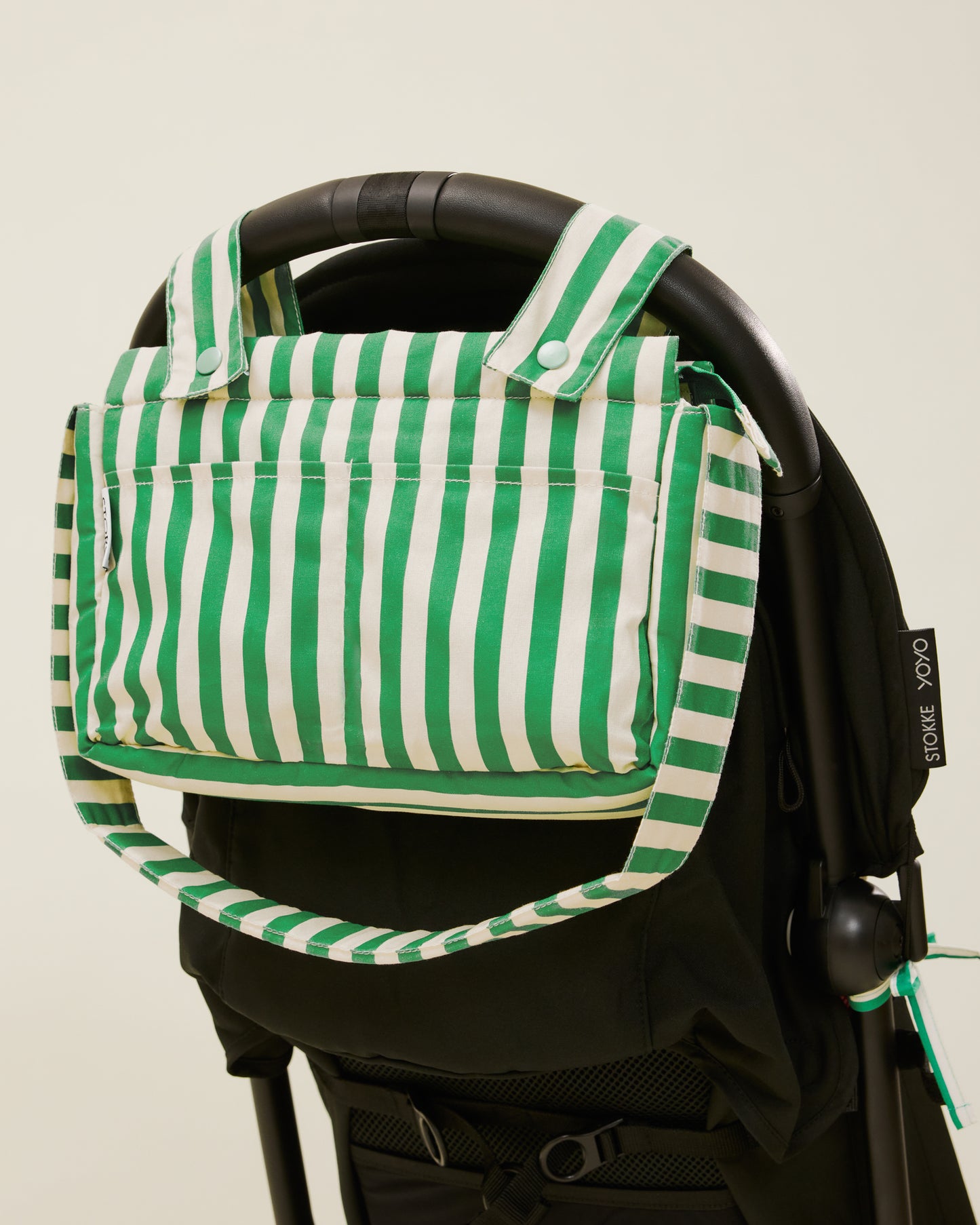 Stroller Party Caddy Bag in Green Stripe, placed on a stroller's handle