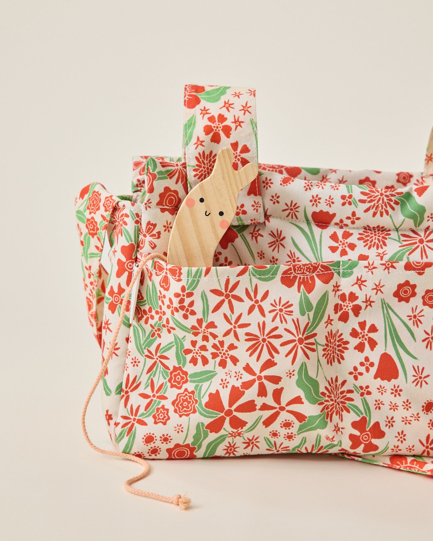 Close up of Stroller Party Caddy Bag in Superbloom with little snail toy peeking out, on a beige background