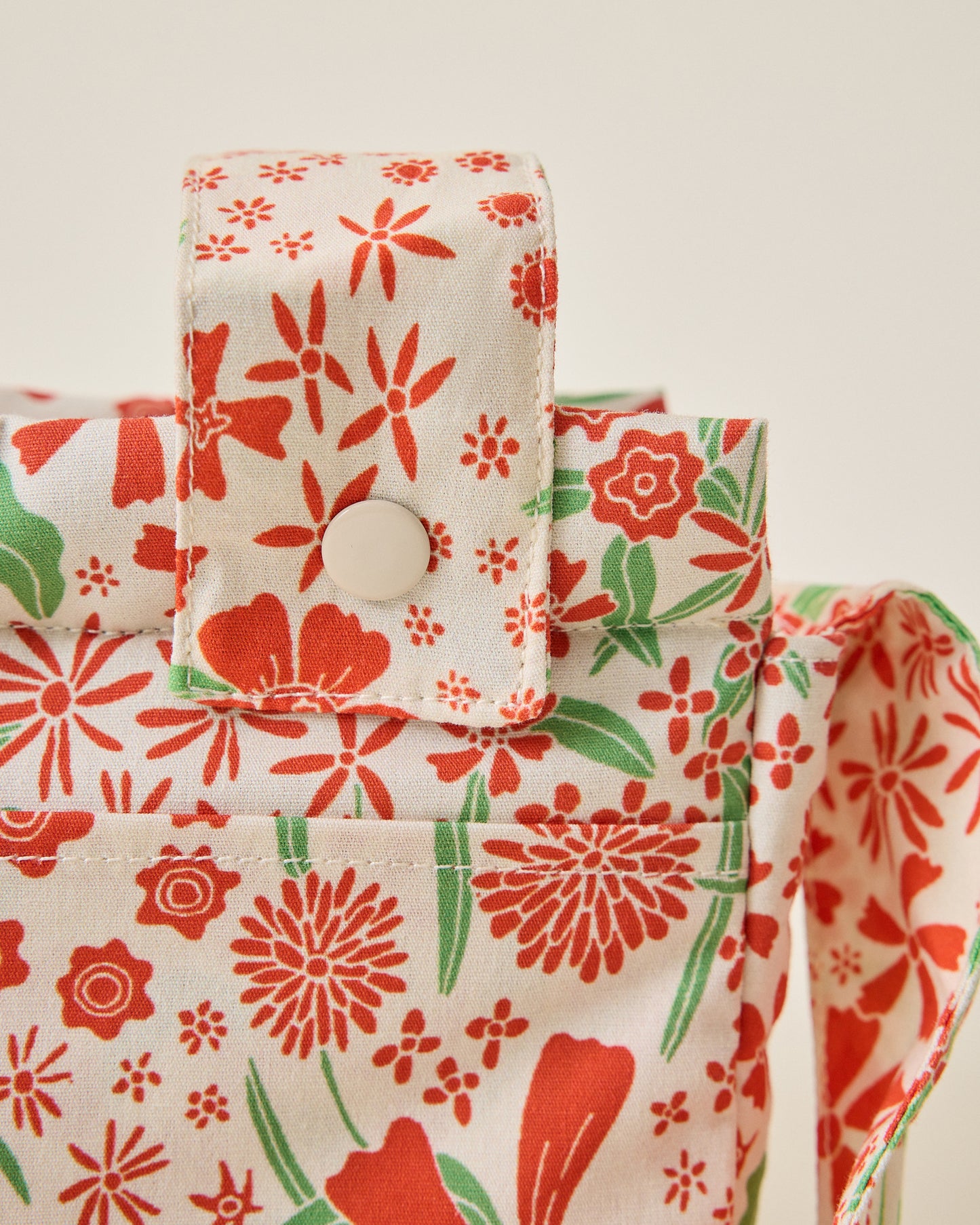 Close up of Stroller Party Caddy Bag snaps in Superbloom on a beige background