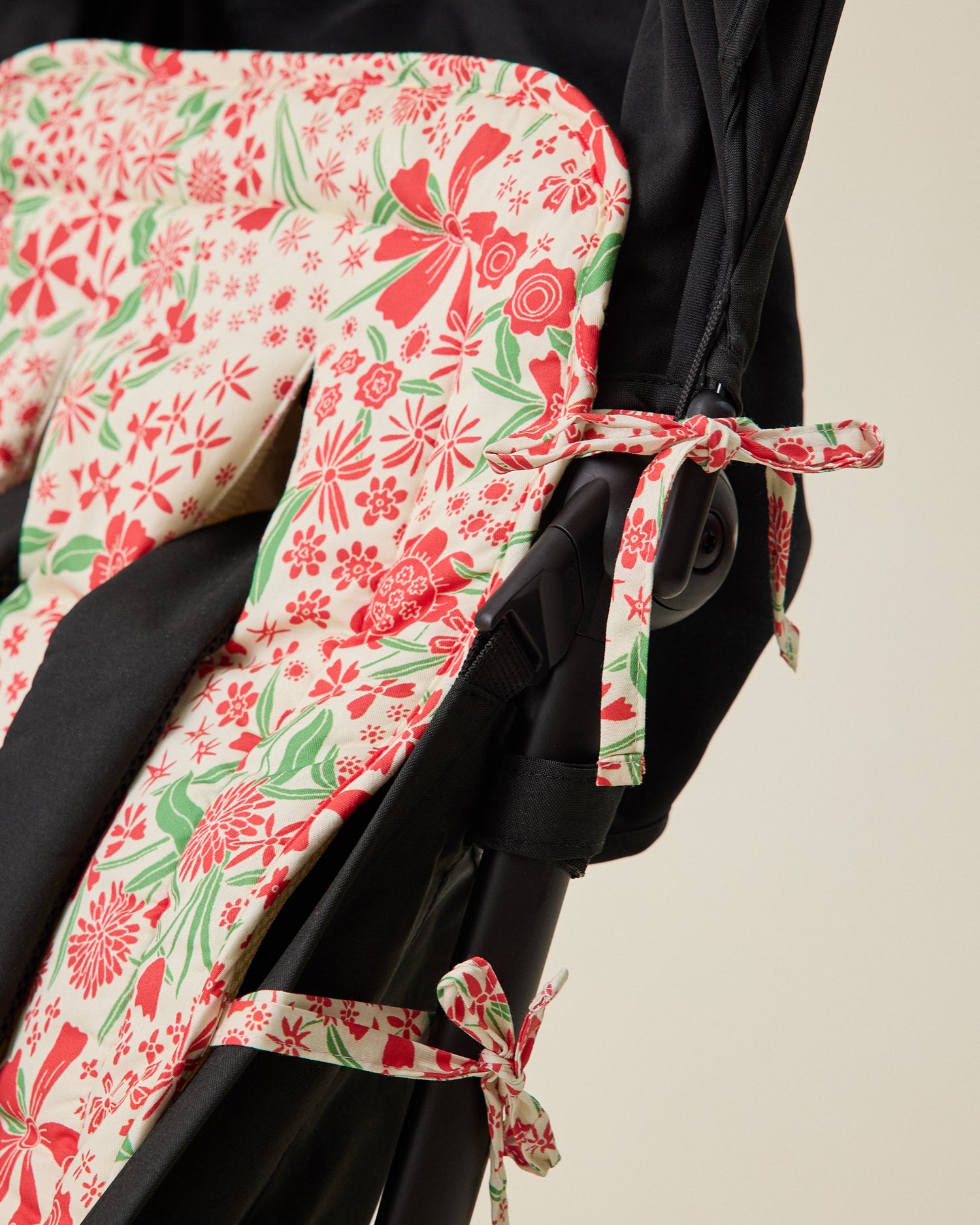 Close up of Stroller Party Seat Liner in Superbloom set in stroller seat to display how ties easily wrap around stroller to secure liner into seat, on a beige background