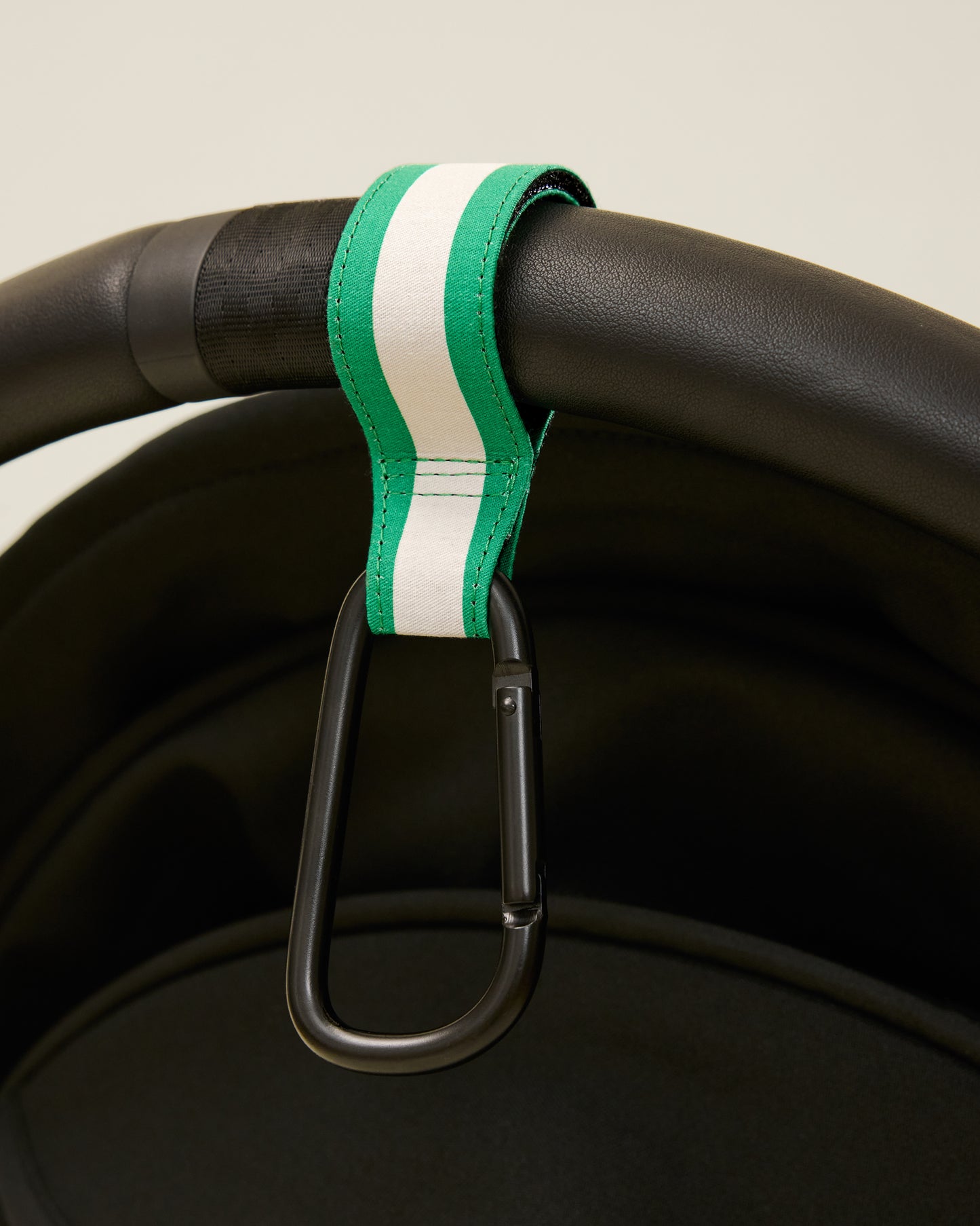 Stroller Party Clips in Green Stripe attached to a stroller's handle