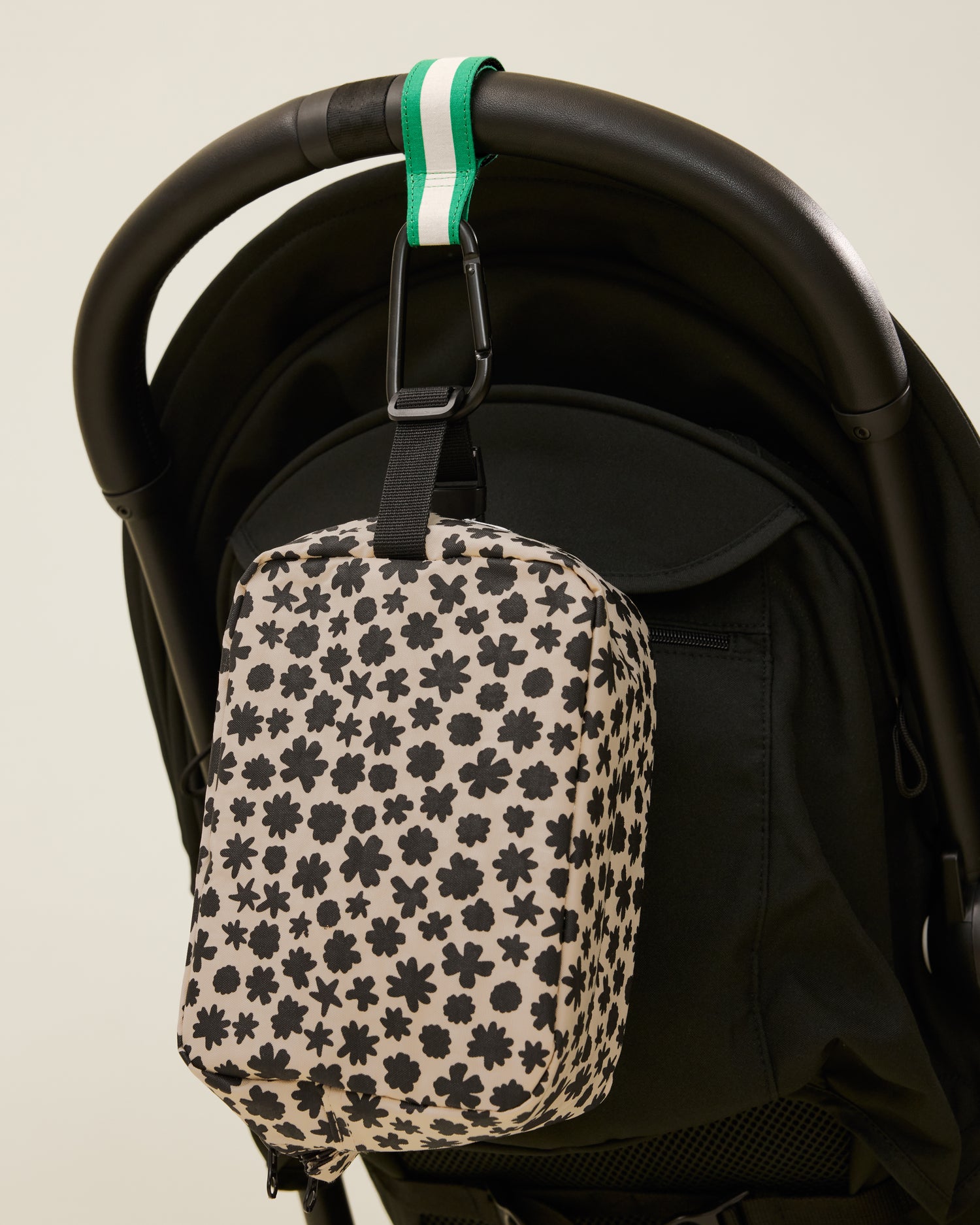 Stroller Party Clips in Green Stripe attached to a stroller's handle and holding a bag