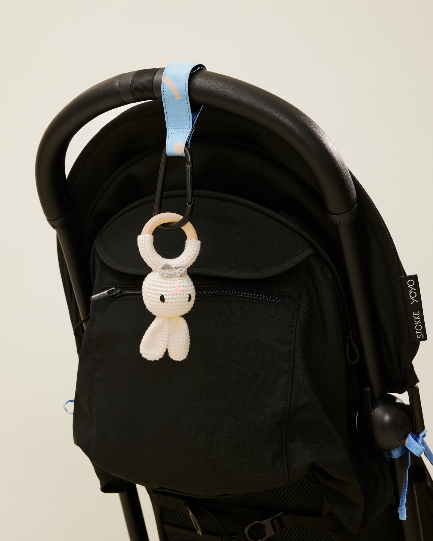 Stroller Party Clips in Sky Squiggles attached to a stroller's handle and holding a toy