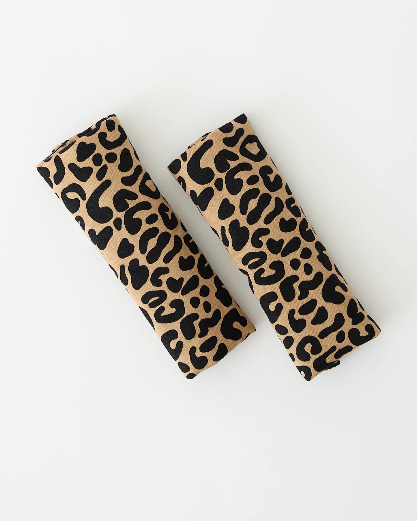 A pair of Stroller Party™ Strap Covers in Leopard pattern, on a beige background.