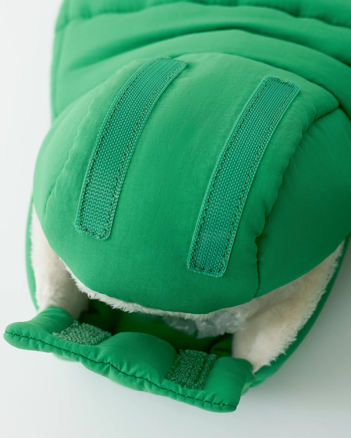 Close up of the velcro and interior fuzzy material on the Cozy Stroller Mitts in Green on an off white background.