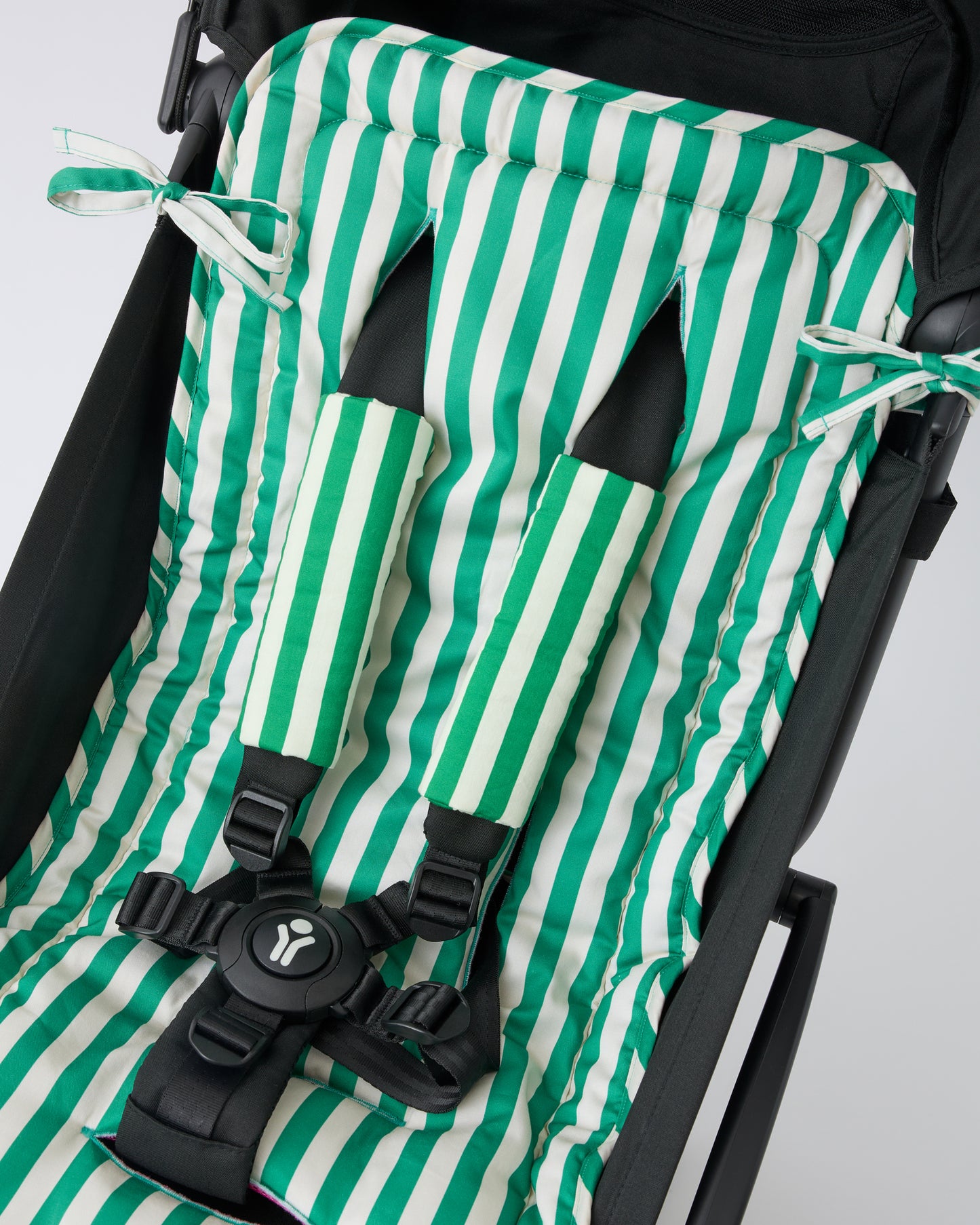 Black stroller with Stroller Party™ Seat Liner in Green Stripe and Stroller Party™ Seat Liner & Strap Covers in Green Stripe on a beige background.