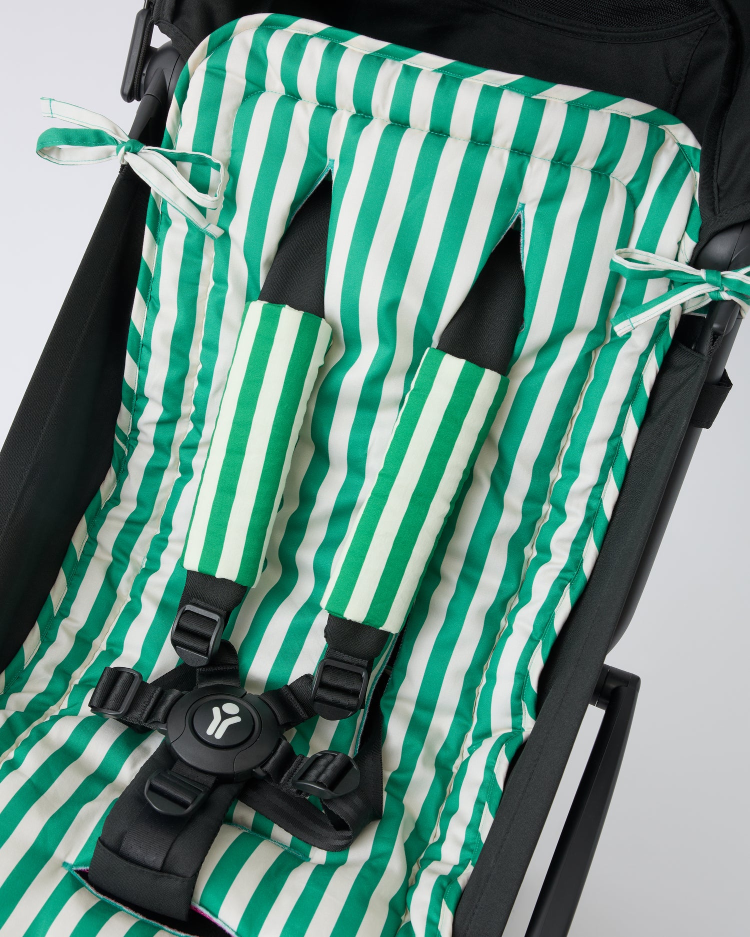 Black stroller with Stroller Party™ Seat Liner in Green Stripe and Stroller Party™ Seat Liner & Strap Covers in Green Stripe on a beige background.