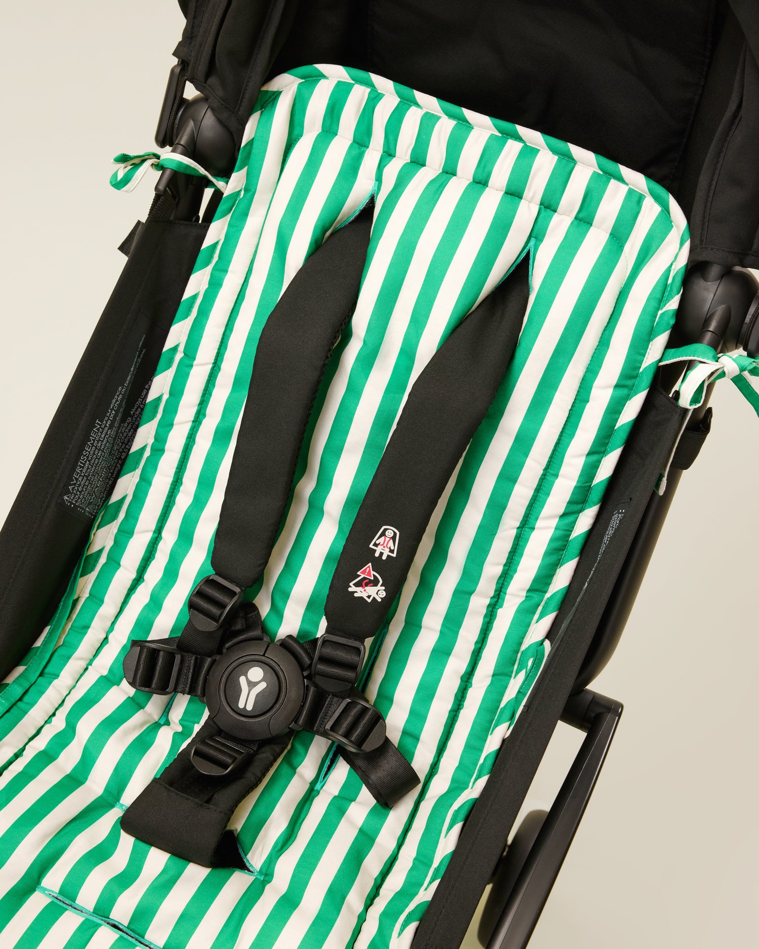Stroller Party Seat Liner in Green Stripe placed on a stroller