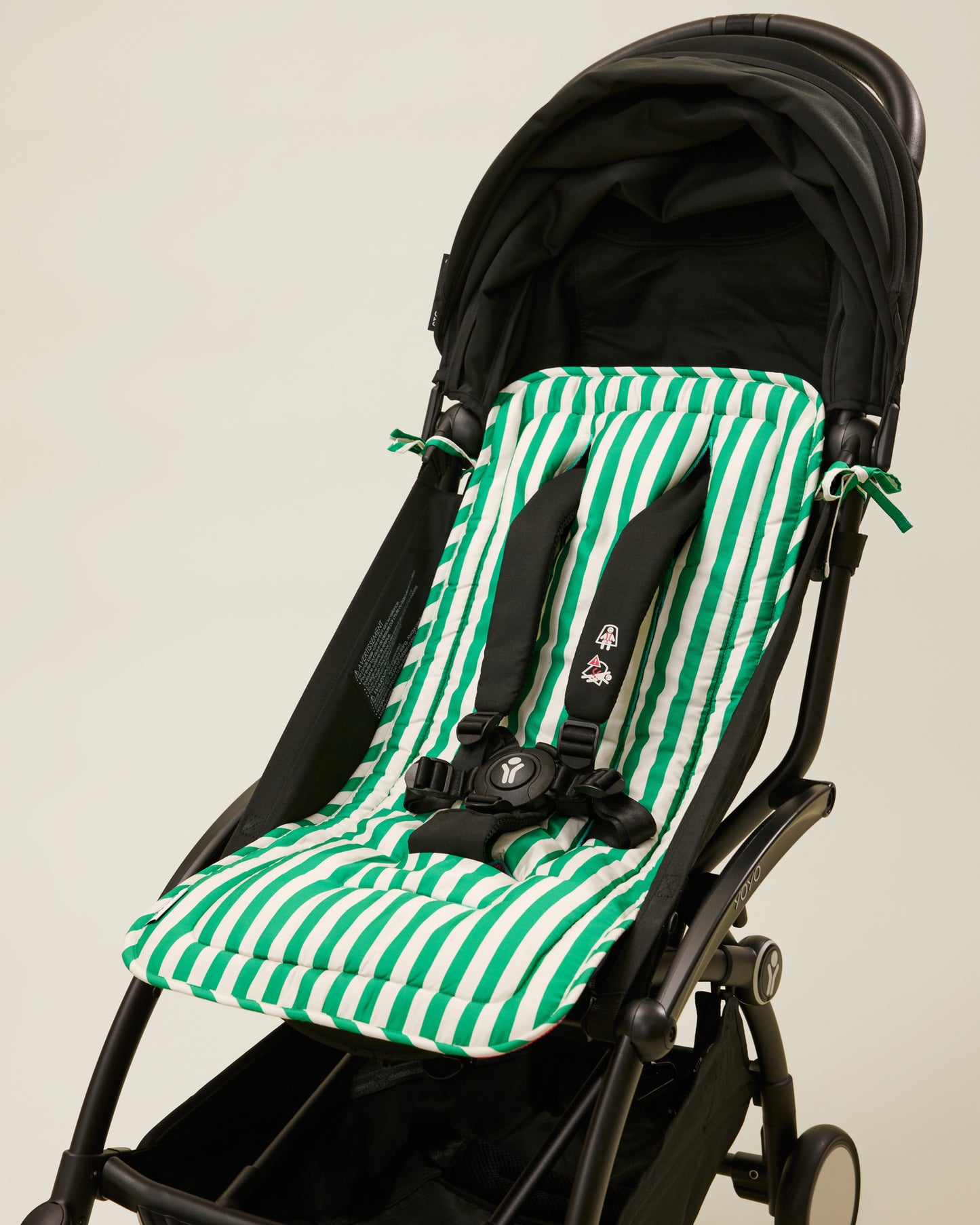 Stroller Party Seat Liner in Green Stripe placed on a stroller