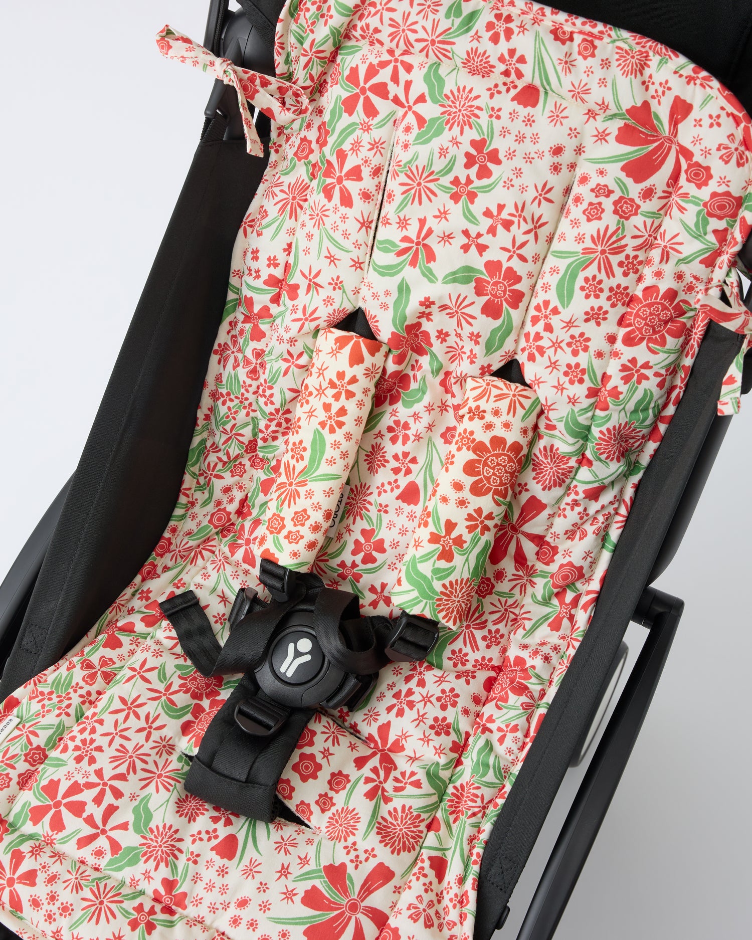 Black stroller with Stroller Party™ Seat Liner & Strap Covers in Superbloom on a beige background.
